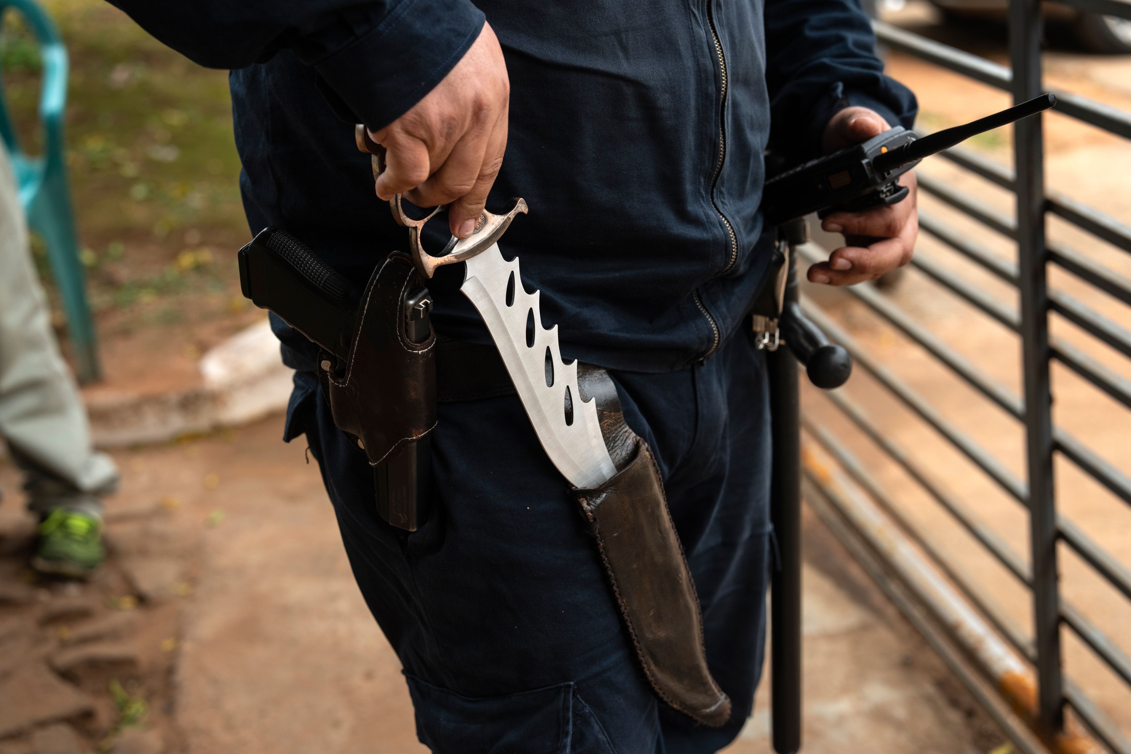 A prison security guard shows the knife he carries as he patrols outside the Regional Penitentiary in Villarica, Paraguay, Saturday, Aug. 31, 2024. (AP Photo/Rodrigo Abd)