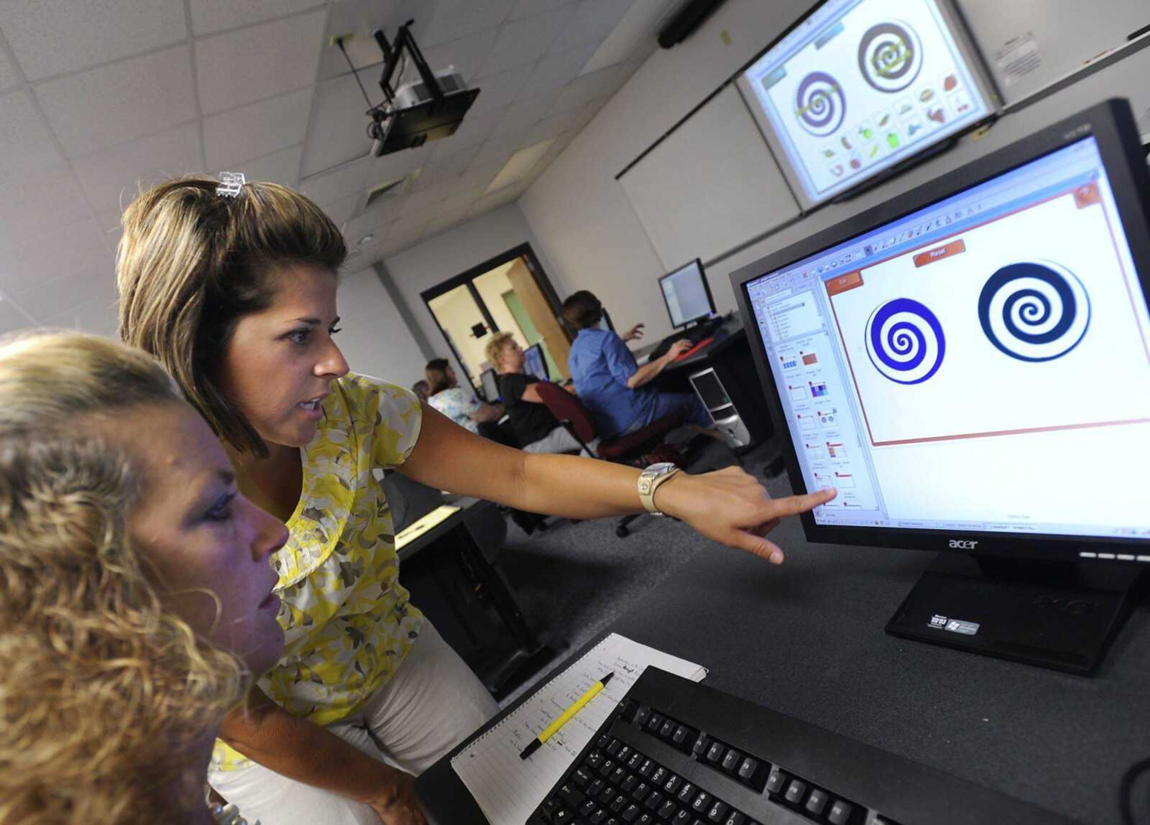 Sarah DeLuca, standing, shows Lora Coots a point about using Smart Boards during their training with other teachers from Alma Schrader Elementary School Tuesday, Aug. 10, 2010 at Southeast Missouri State University. The board is a modern interactive version of the traditional chalk board. Stimulus funds helped pay for new Smart Boards to be installed in almost every classroom at Alma Schrader for this school year. (Fred Lynch)