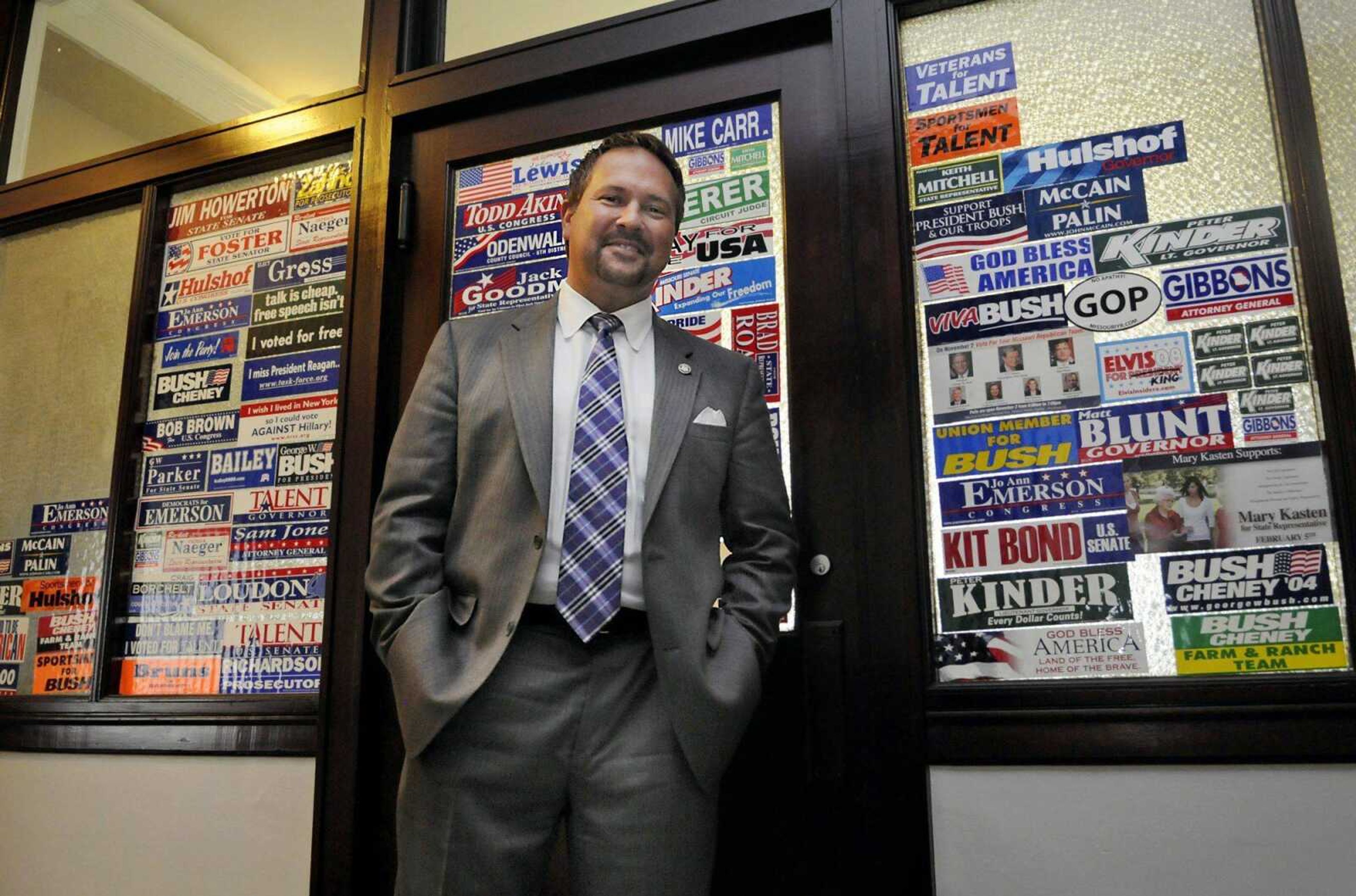 David Barklage, President of the Barklage Company, a political consulting firm, stands in front of his office window displaying stickers from the various campaigns he has worked on. (KRISTIN EBERTS)