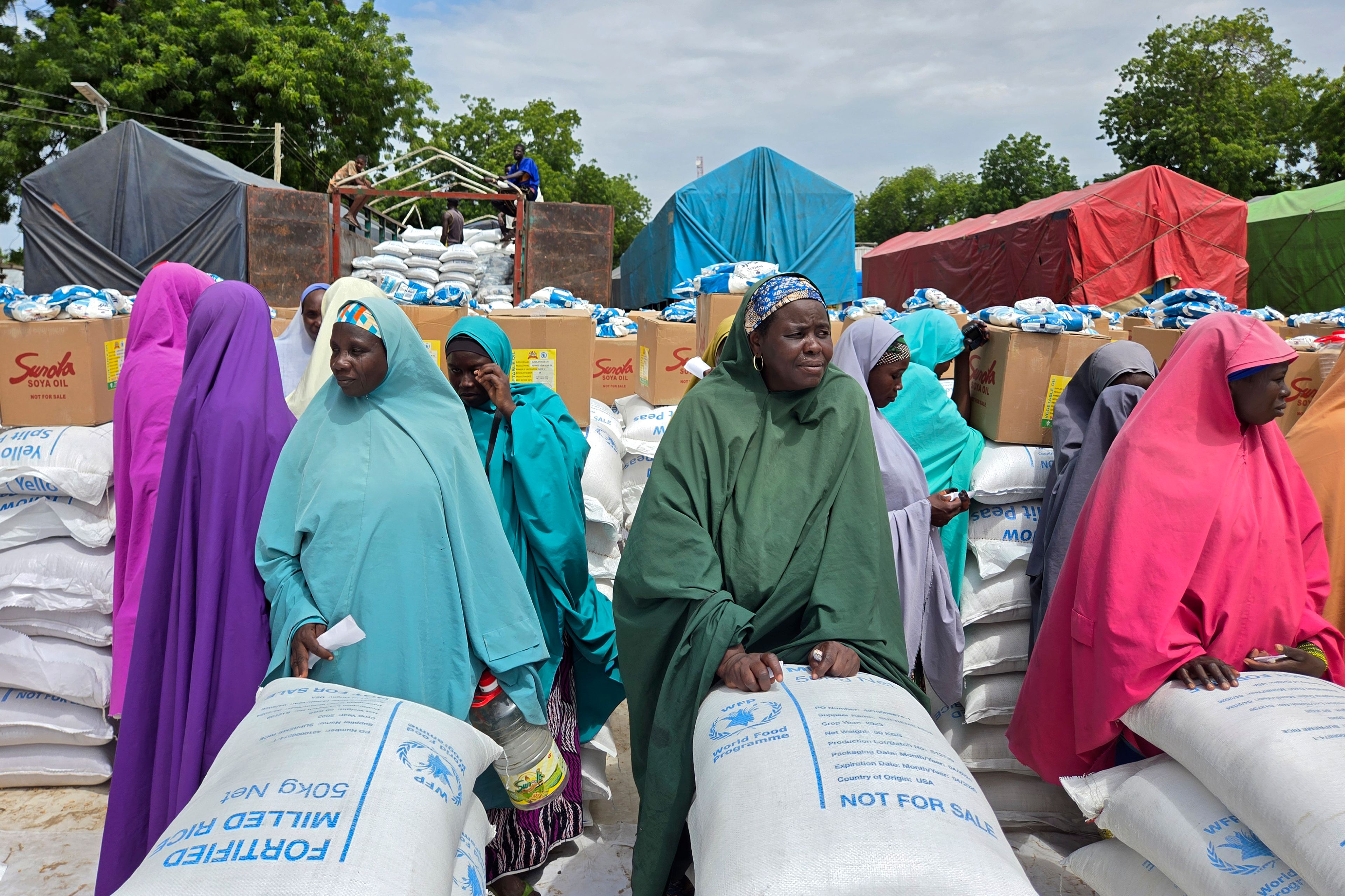 Women and villagers wait to receive food donations from the United Nations World Food Program in Damasak, northeastern Nigeria, Sunday, Oct. 6, 2024. (AP Photo/Chinedu Asadu)