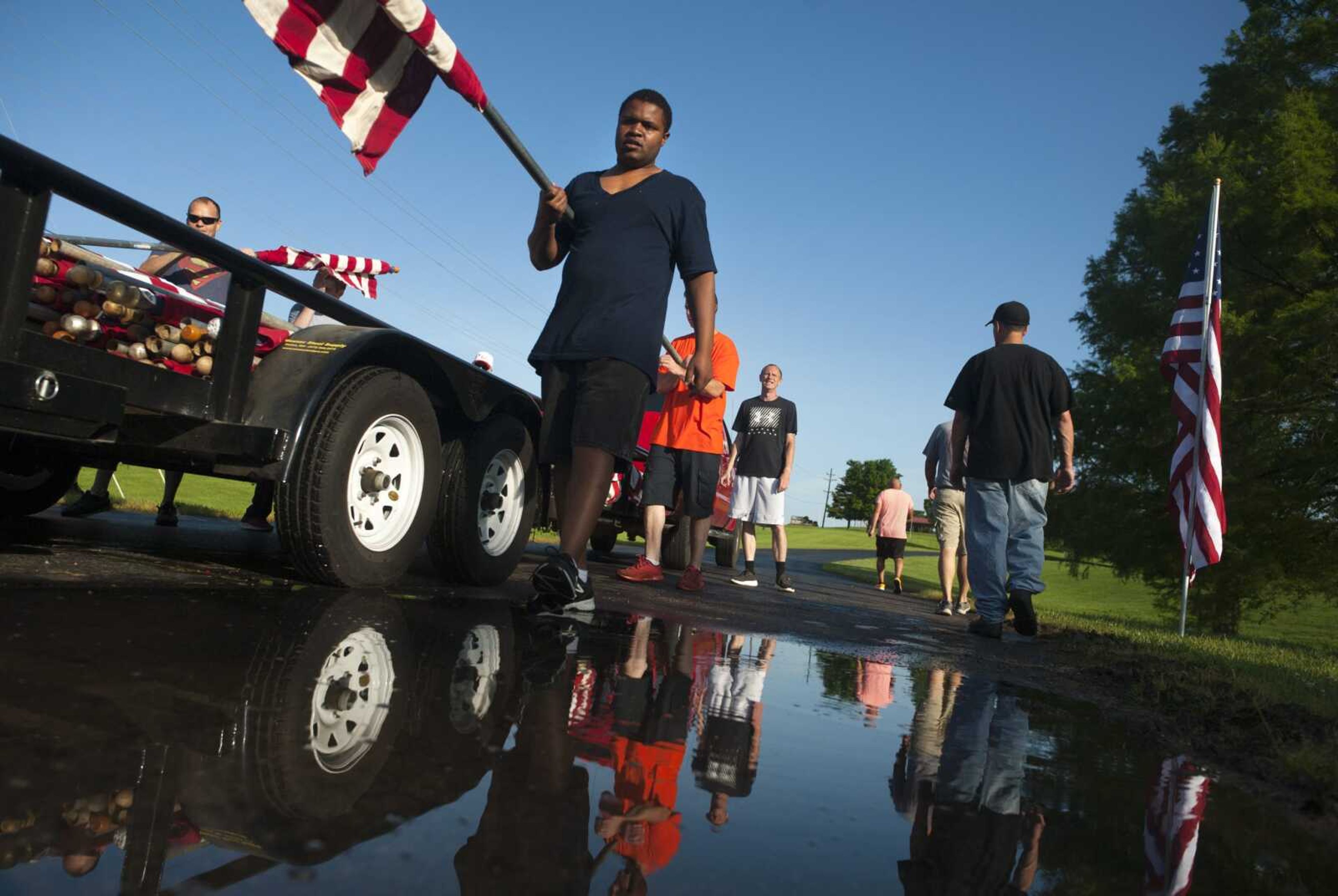 Thomas Houston, front, carries a flag while working with fellow crew members from Adult and Teen Challenge Mid-America to assemble the Avenue of Flags for Memorial Day on Monday at Cape Girardeau County Park North in Cape Girardeau.