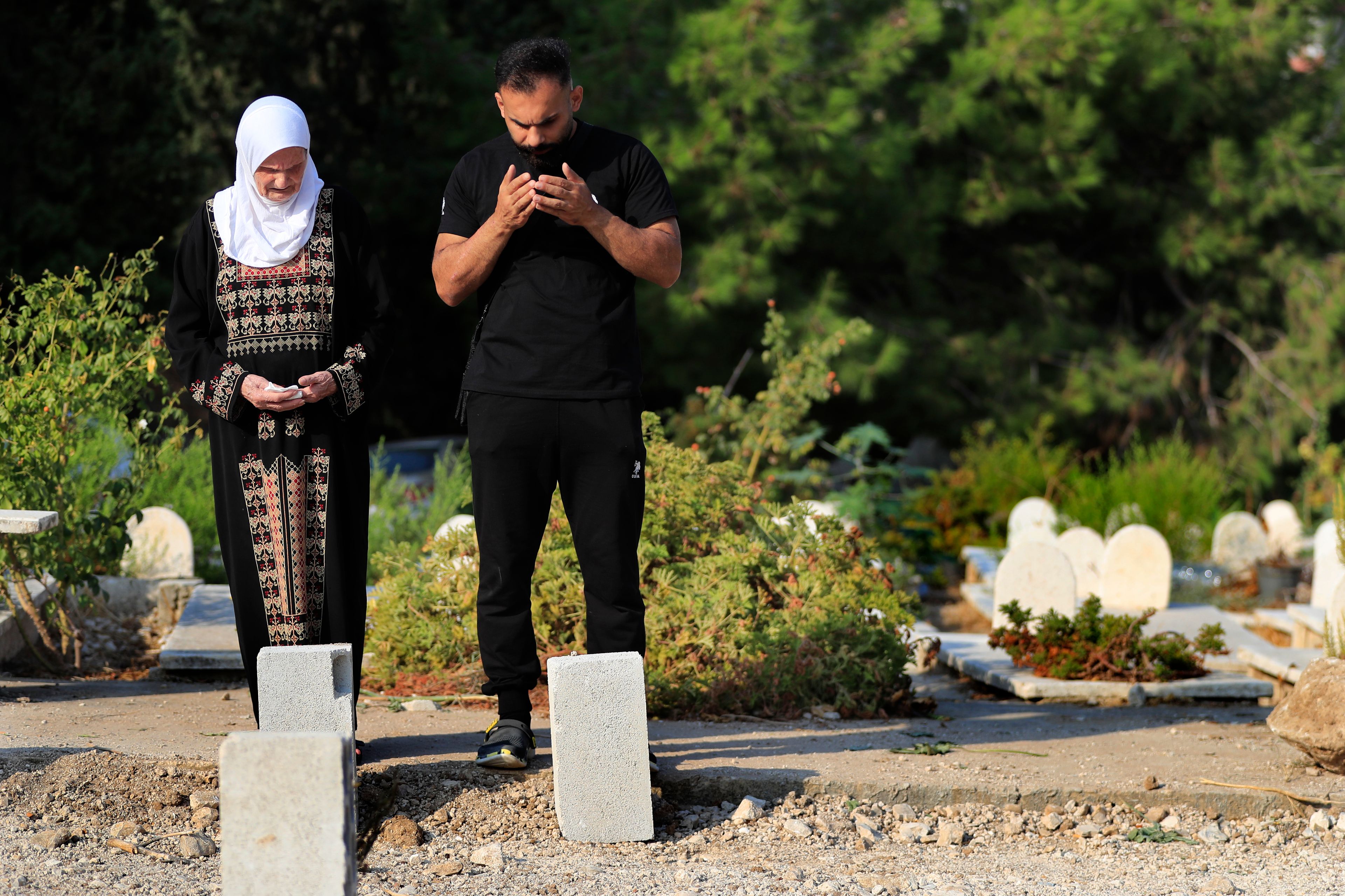 Jamileh, left, and Achraf Ramadan pray at a cemetery for their relatives who were killed on Sept. 29 during the deadliest Israeli airstrike on a residential building, in the southern port city of Sidon, Lebanon, Thursday, Oct. 10, 2024. (AP Photo/Mohammed Zaatari)