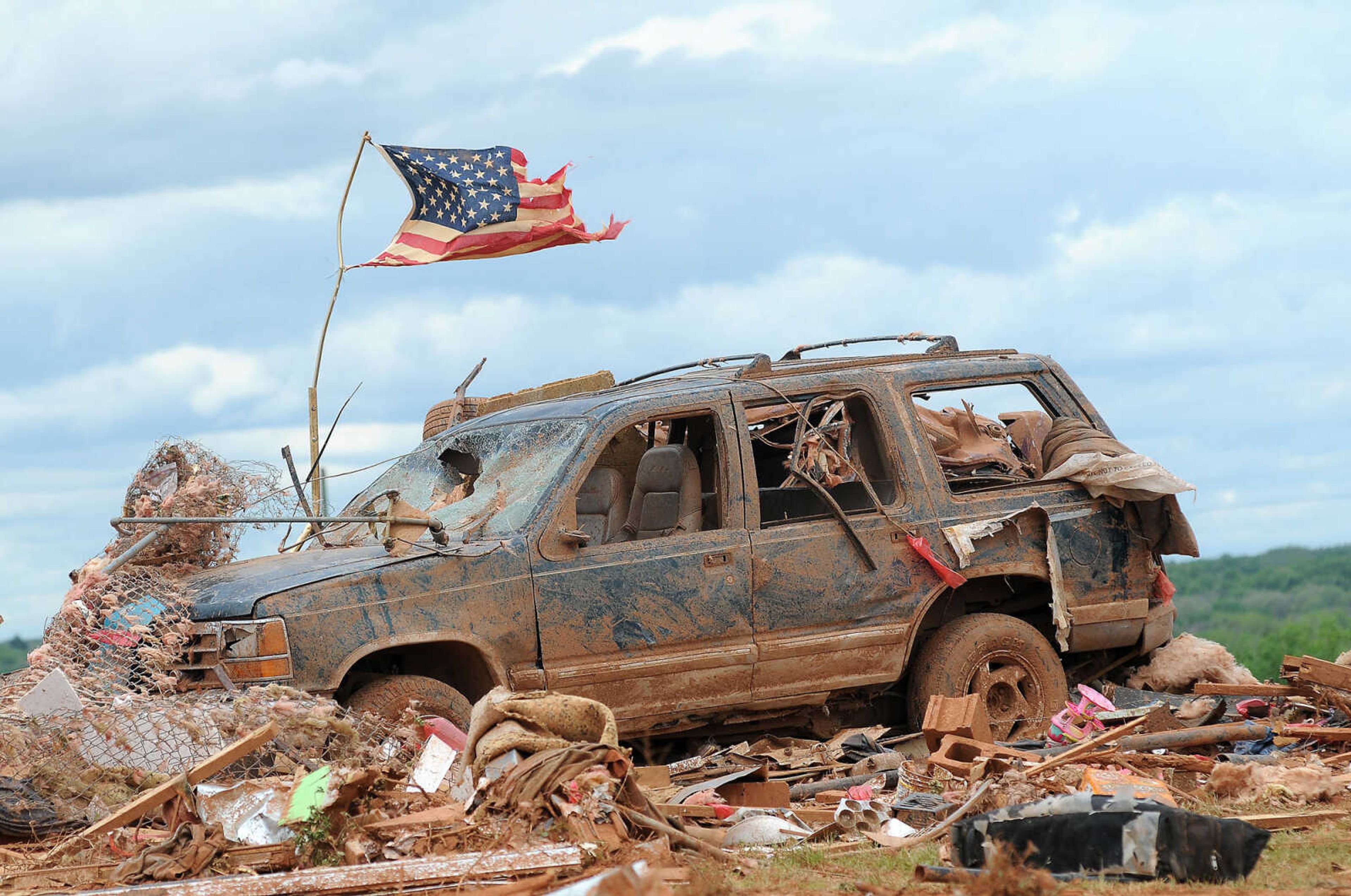 A tattered American flag flies over a vehicle where two young girls ages 5 and 7 were found after a severe thunderstorm spawned a massive tornado at Hideaway Mobile Home Villa in Woodward, Oklahoma shortly after midnight Sunday, April 15, 2012. The girls, Faith and Kelley Hobbie, ages 5 and 7, and their father, Frank Hobbie, were three of the five fatalities in the Northwest Oklahoma destruction. (AP Photo/ENID NEWS and EAGLE, BONNIE VCULEK)