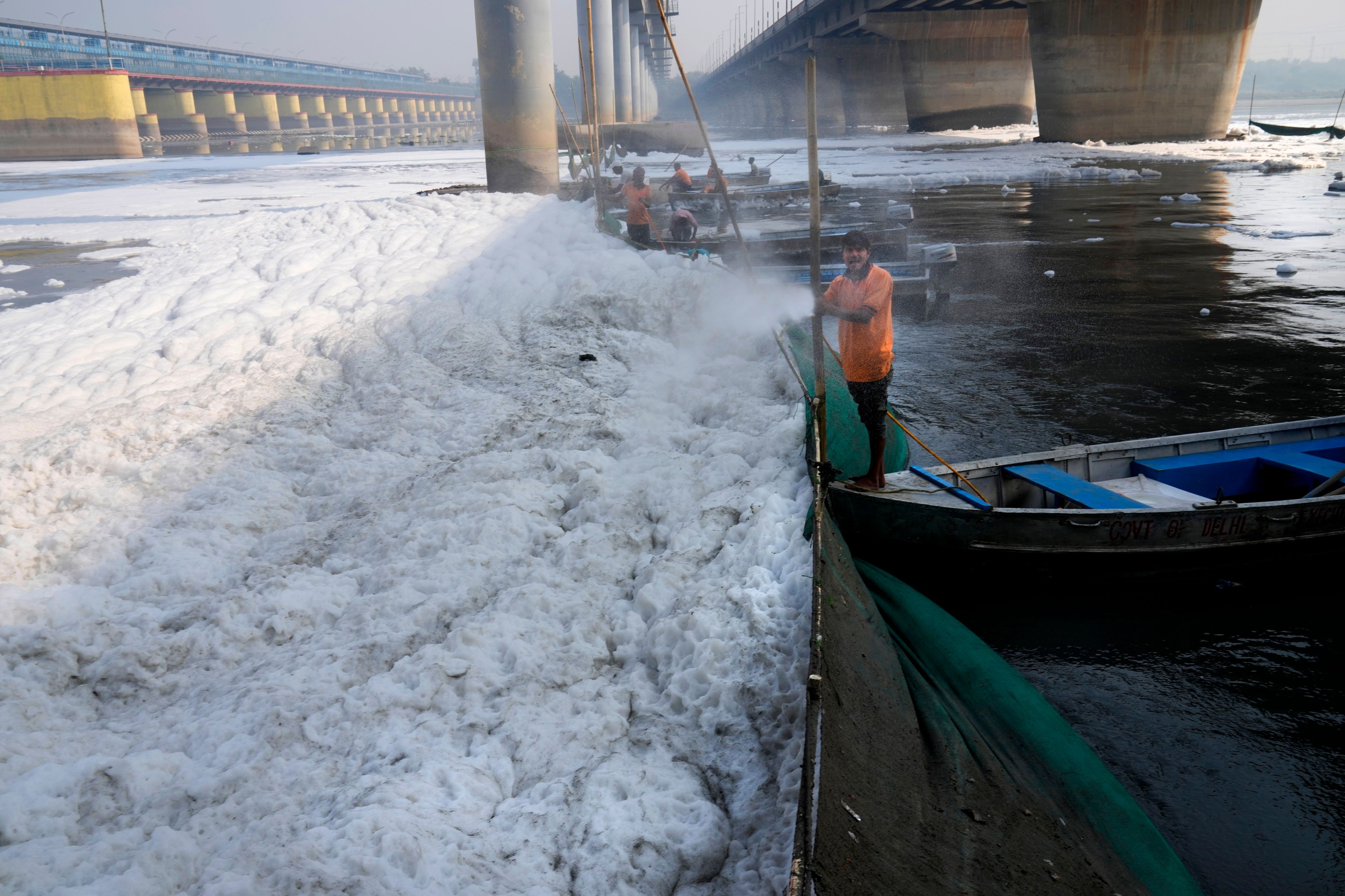 A worker for the Delhi Jal or water board sprays chemical to clean the toxic foams in the river Yamuna in New Delhi, India, Tuesday, Oct. 29, 2024. (AP Photo/Manish Swarup)