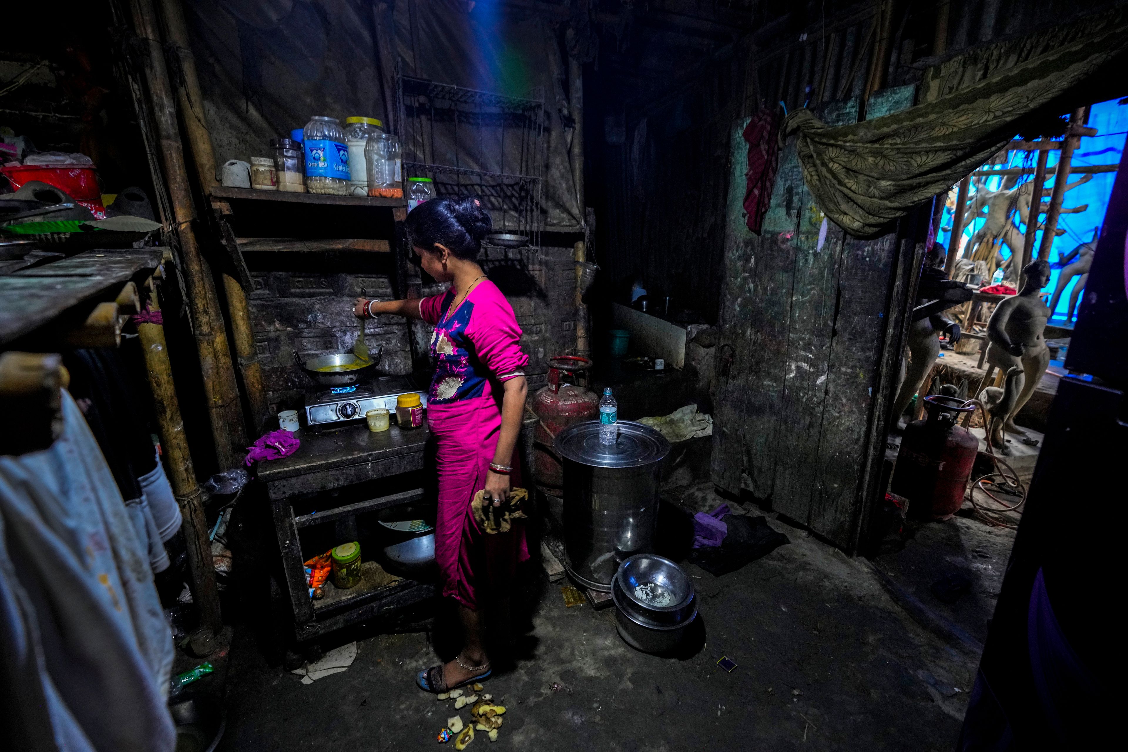 Sunita Paul, 31, prepares food for herself and other artisans preparing mud idols of the Hindu goddess Durga and other deities at a workshop during the Durga Puja festival in Guwahati, India, Friday, Oct. 4, 2024. (AP Photo/Anupam Nath)