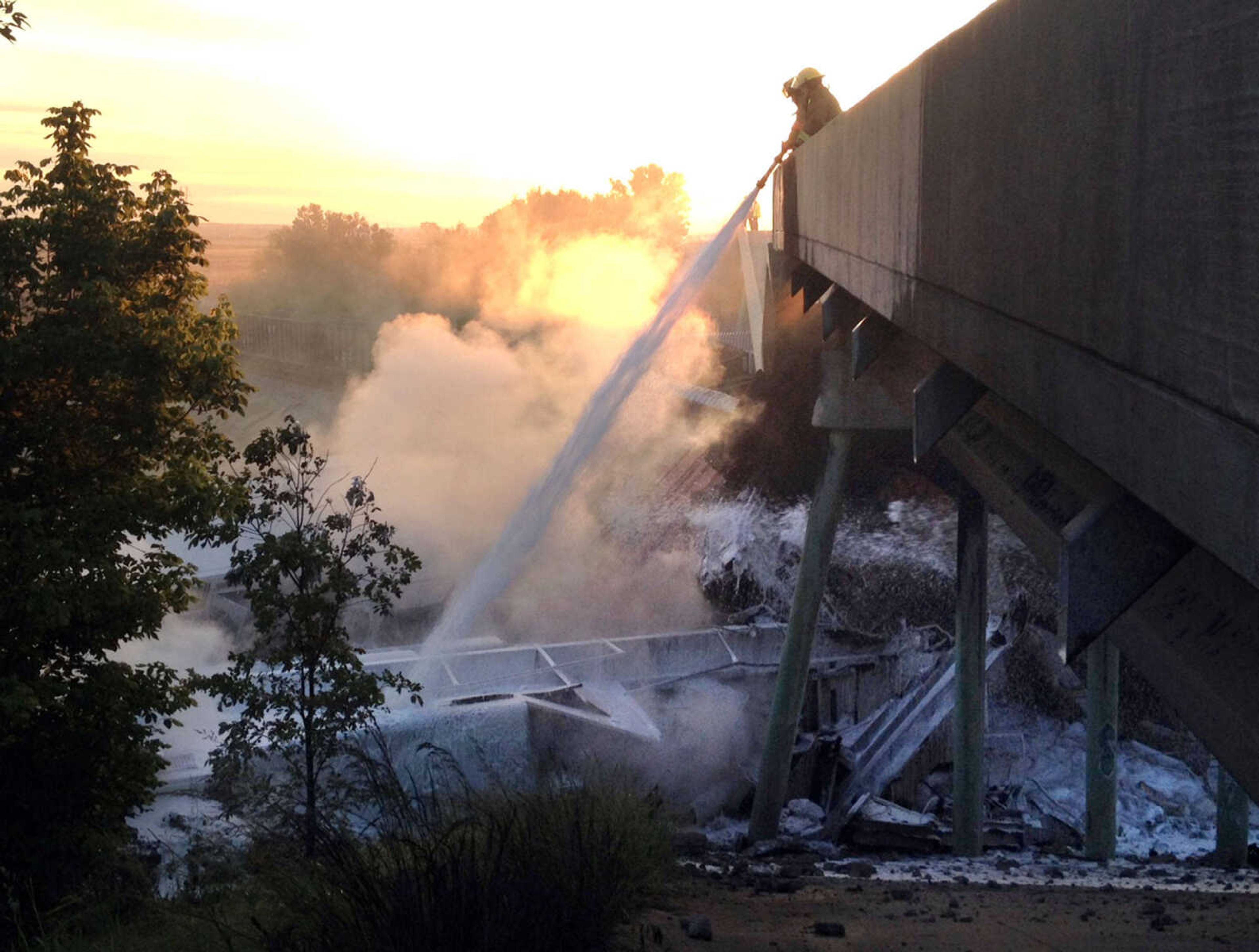 Firefighters Adam Eftink and Anthony Odum with the Sikeston Department of Public Safety help to extinguish flames at the site where two trains collided near Rockview, Mo. on Saturday, May 25, 2013. (Provided/Michael O'Brien)