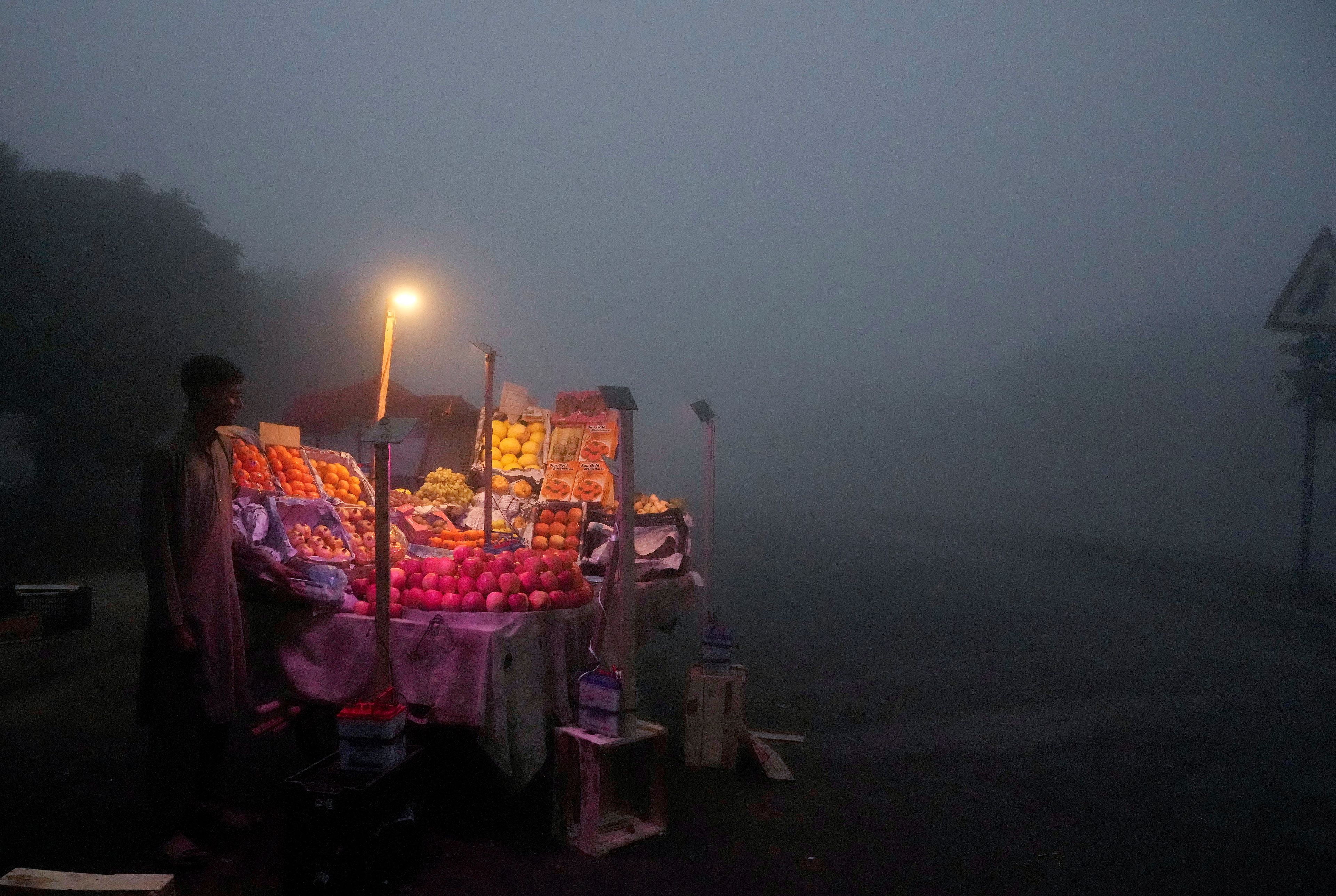 A fruit seller arranges his stall in early morning as smog envelopes the area of Lahore, Pakistan, Thursday, Nov. 14, 2024. (AP Photo/K.M. Chaudary)