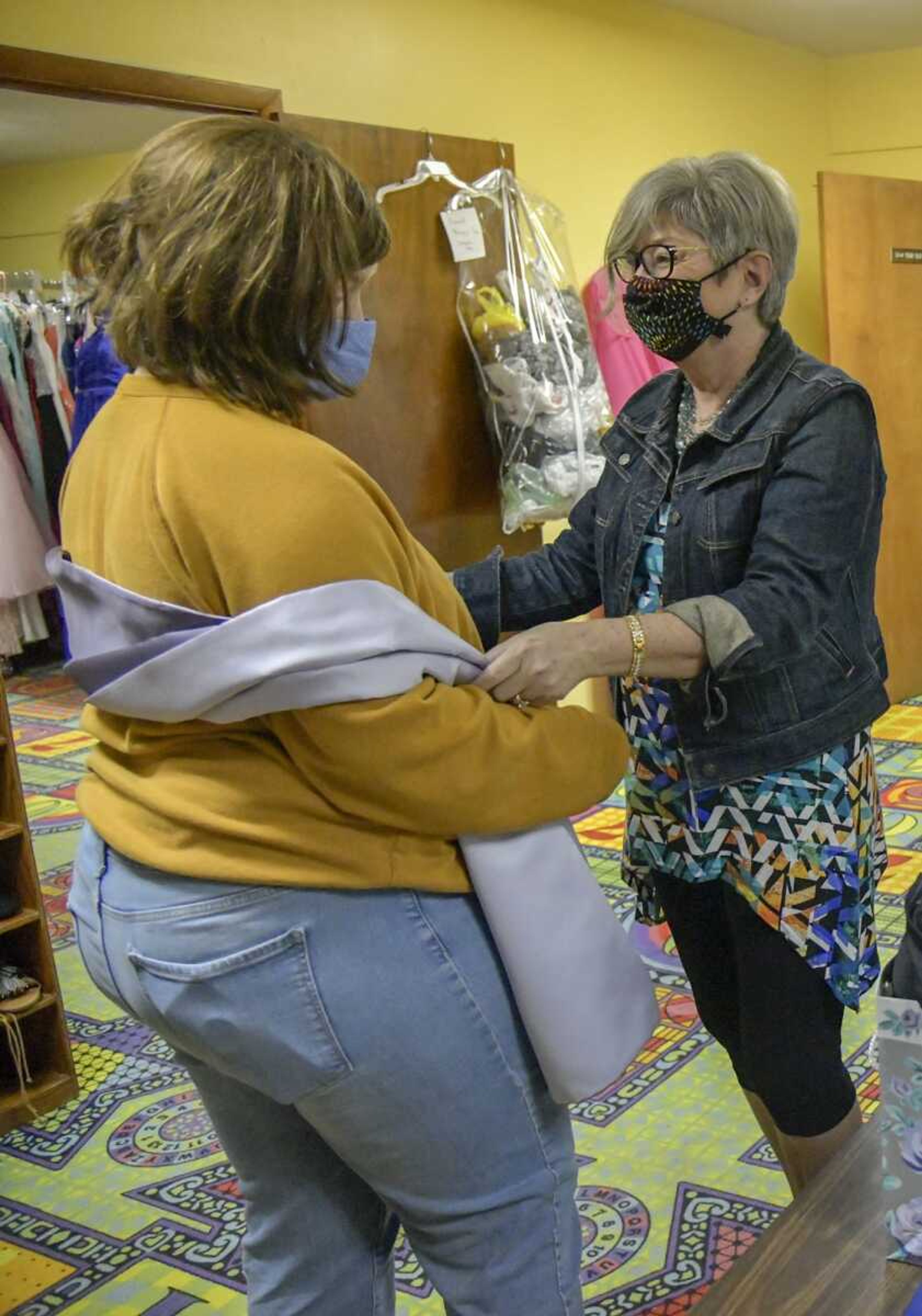 Shop volunteer Brenda Randolph shows Bekka Bollinger how she can wear the shall with her chosen dress for prom at the Westminster Presbyterian Church in Cape Girardeau on Tuesday, March 16, 2021.