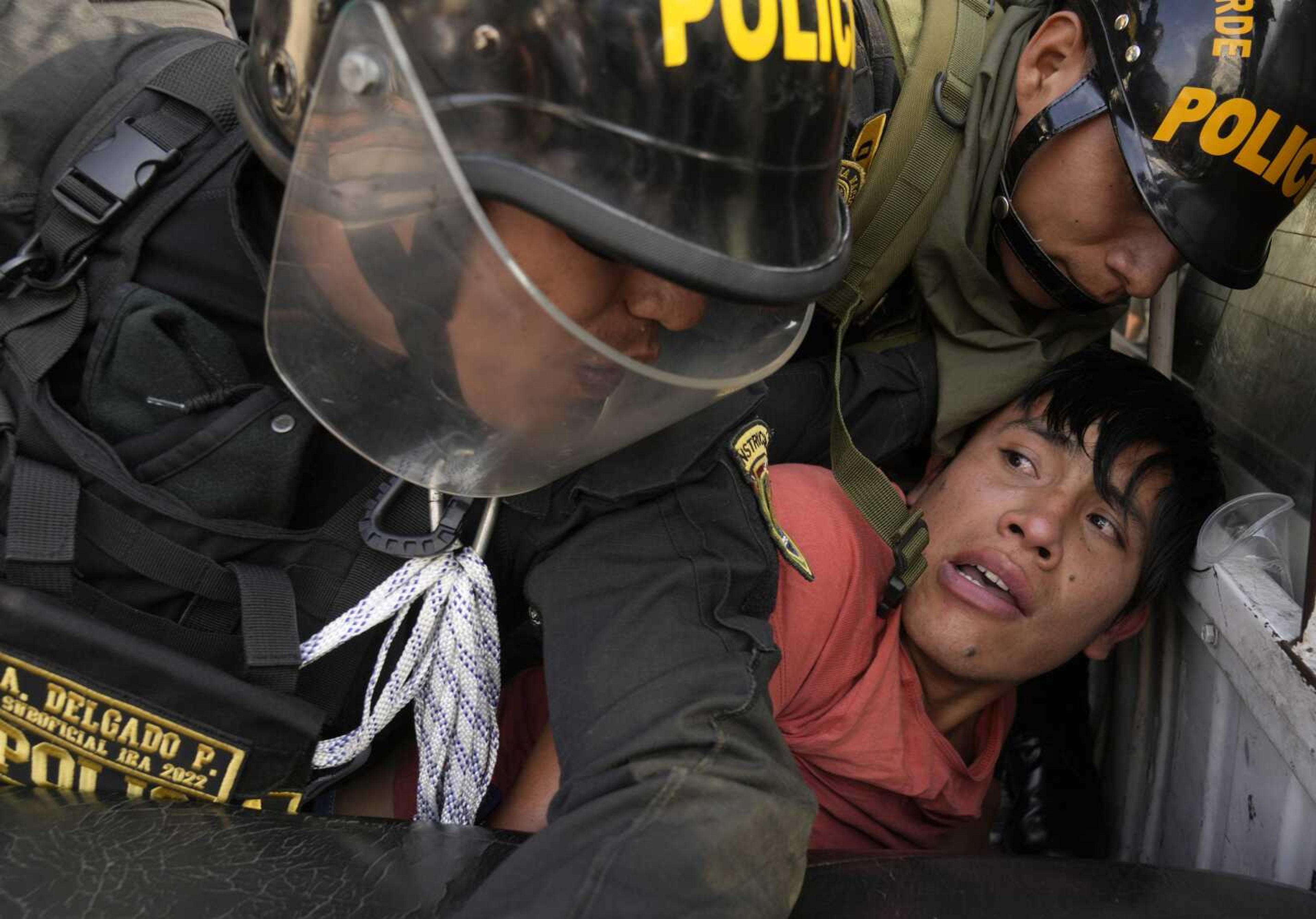 An anti-government protester who traveled to the capital from across the country to march against Peruvian President Dina Boluarte is detained and thrown on the back of police vehicle Thursday during clashes in Lima, Peru. Protesters are seeking immediate elections, Boluarte's resignation, the release of ousted President Pedro Castillo and justice for up to 48 protesters killed in clashes with police.