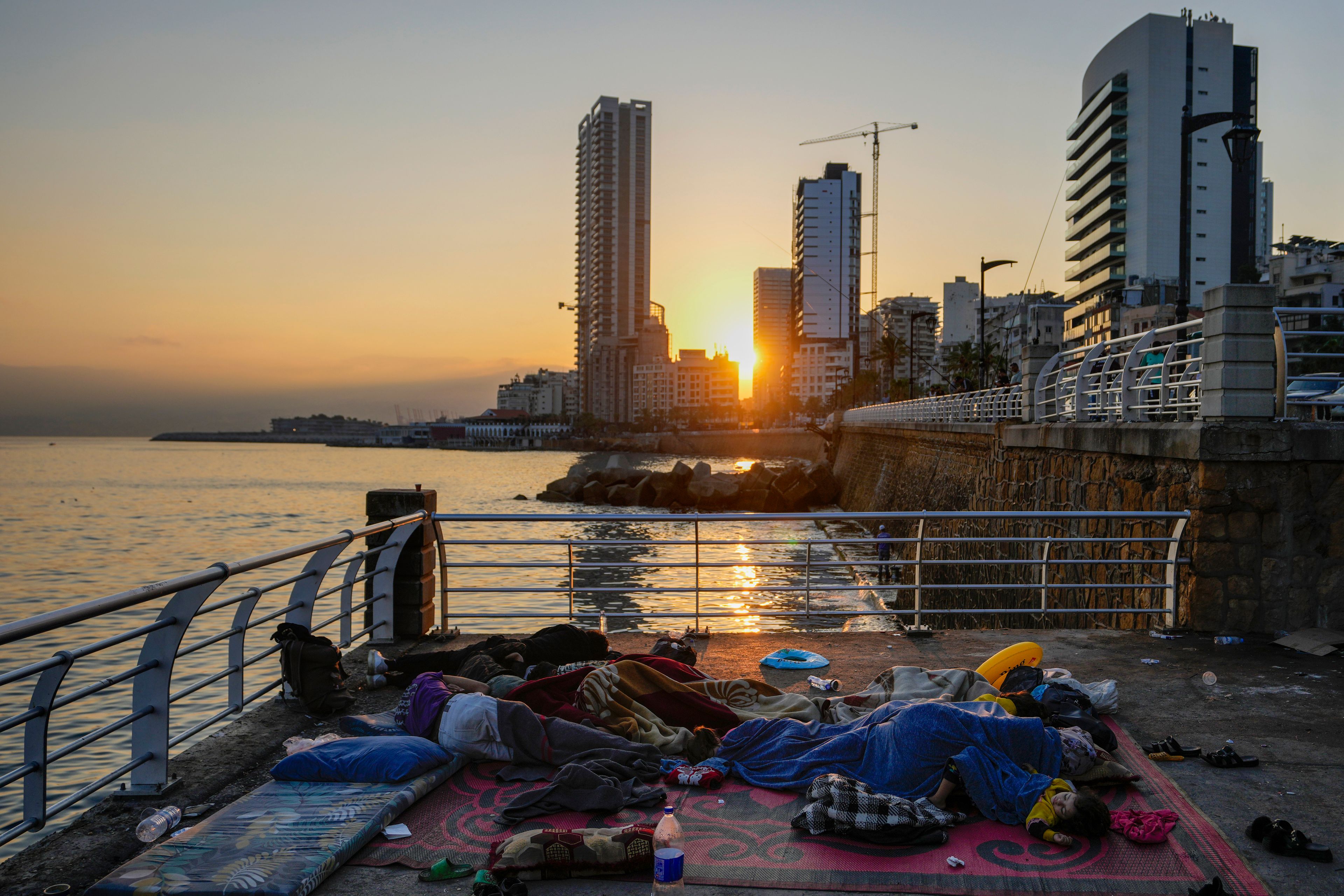 Families sleep on Beirut's corniche after fleeing the Israeli airstrikes in Beirut's southern suburb, Lebanon, Monday, Sept. 30, 2024. (AP Photo/Hassan Ammar)