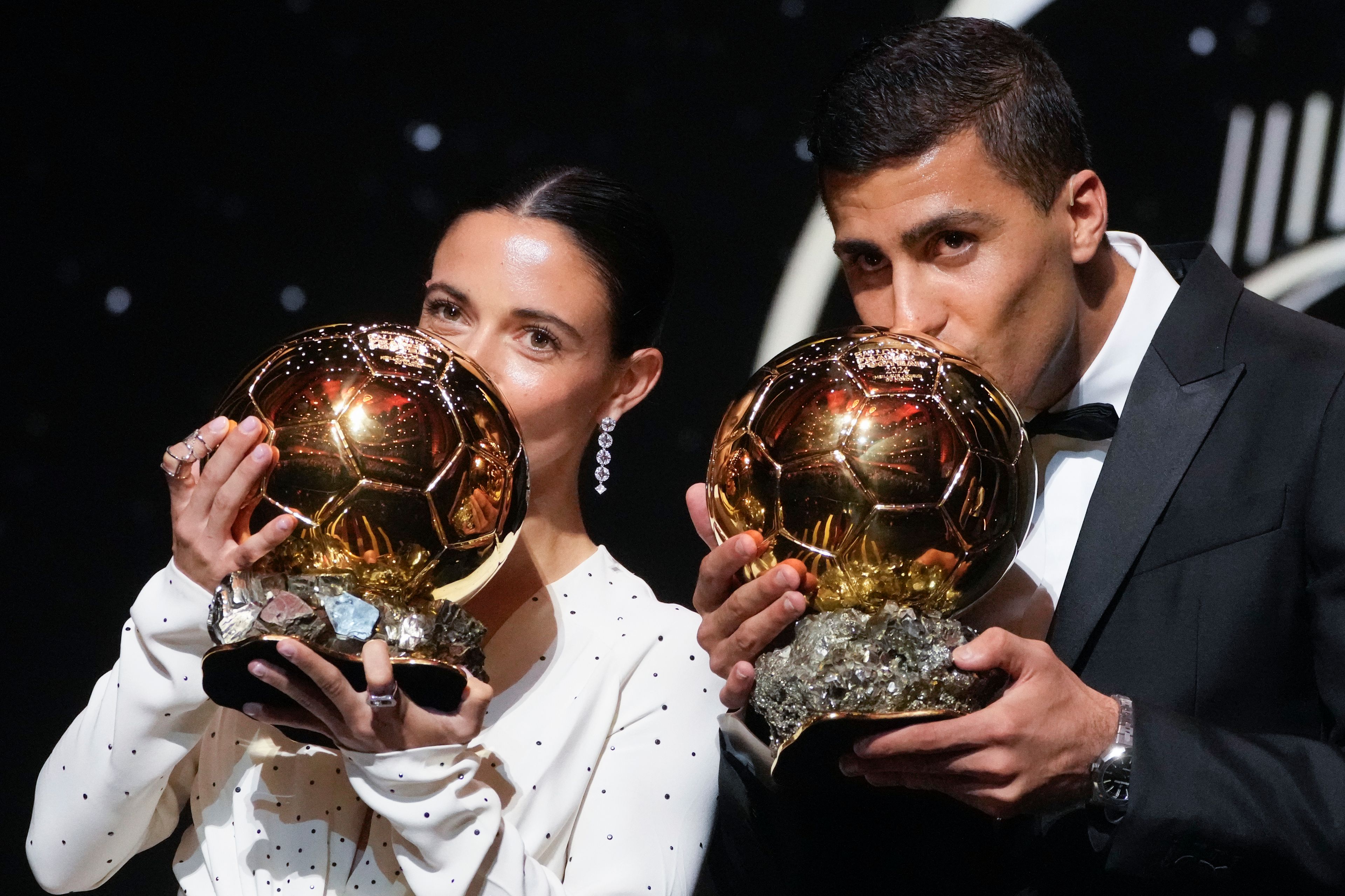 Barcelona's Spanish player Aitana Bonmati, left, and Manchester City's Spanish player Rodri kiss their 2024 Ballon d'Or trophies during the 68th Ballon d'Or (Golden Ball) award ceremony at Theatre du Chatelet in Paris, Monday, Oct. 28, 2024. (AP Photo/Michel Euler)