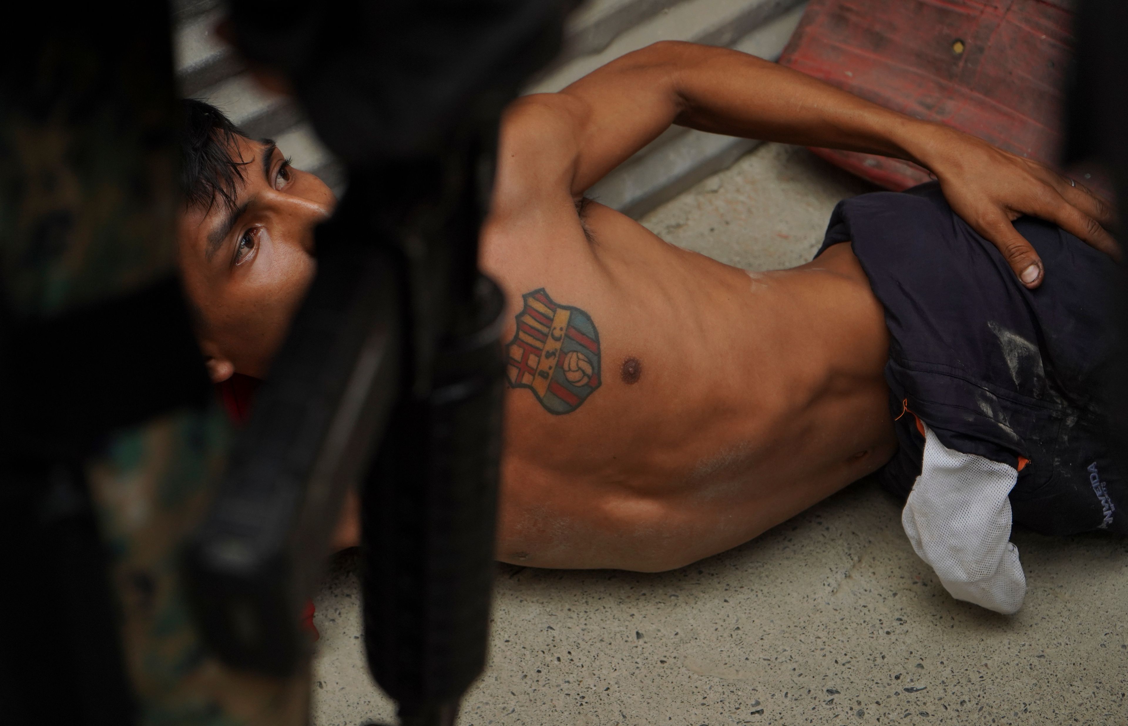 A resident lies on the floor of a home as military and police officers conduct a raid as part of a joint operation searching for weapons and drugs in a neighborhood of Guayaquil, Ecuador, Oct. 16, 2024. (AP Photo/Cesar Munoz)