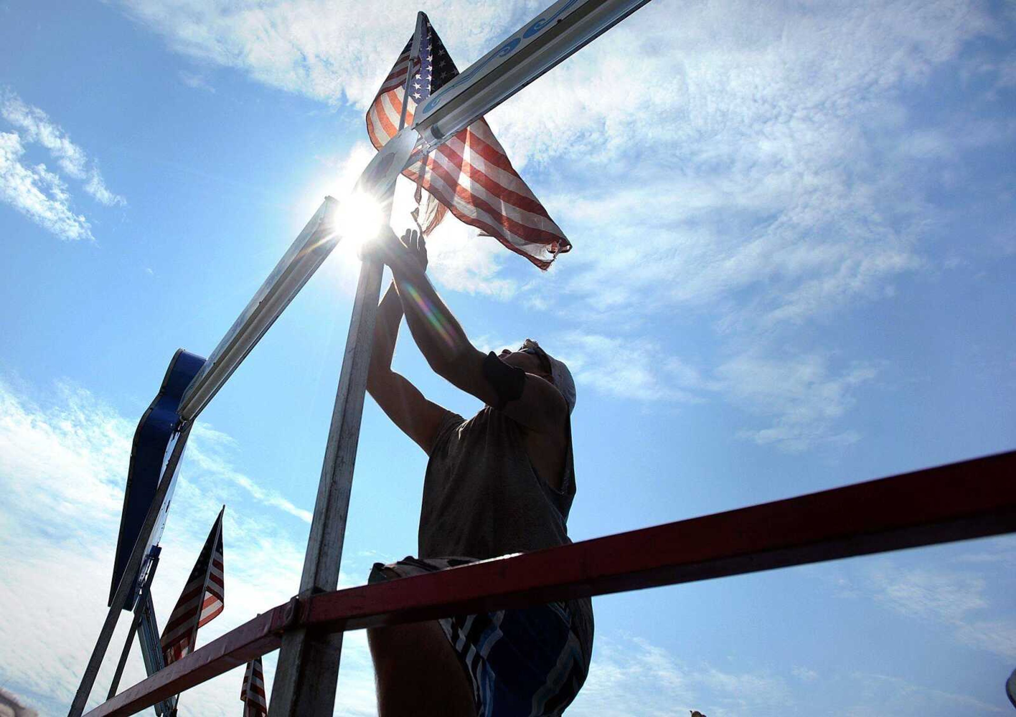 Julio Cesar of Lowery Carnival Co. hangs an American flag from the top railing of the Tilt-A-Whirl on Thursday at Arena Park in Cape Girardeau. The SEMO District Fair gets underway Saturday and runs through Sept. 14. (Laura Simon)