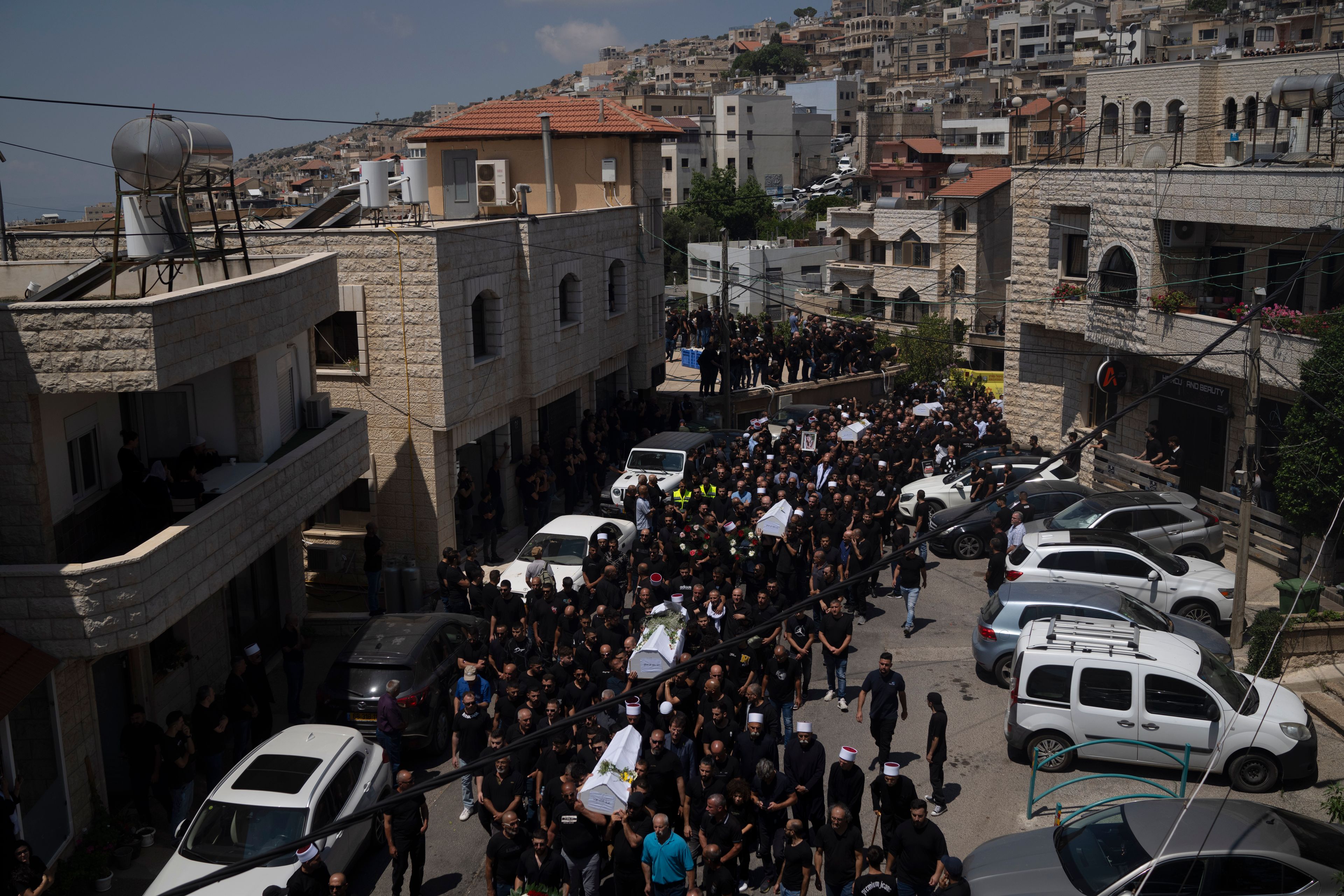 Mourners from the Druze minority carry the coffins of some of the 12 children and teens killed in a rocket strike at a soccer field during their funeral, in the village of Majdal Shams, in the Israeli-annexed Golan Heights, Sunday, July 28, 2024. It's the deadliest strike on an Israeli target along the country's northern border since the fighting between Israel and the Lebanese militant group Hezbollah began. (AP Photo/Leo Correa)