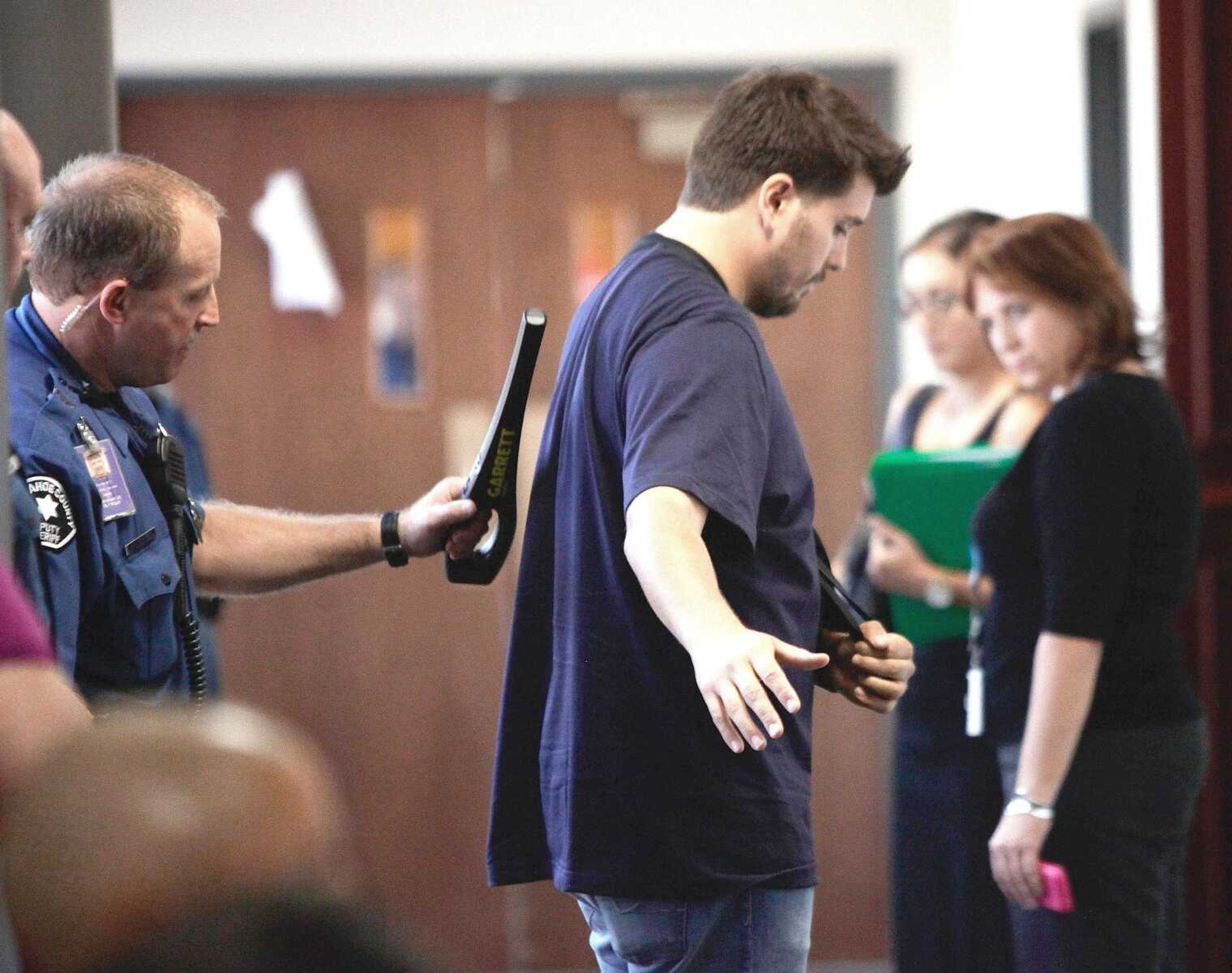 A sheriffs deputy wands shooting victim Pierce O&#8217;Farrill on Thursday as he enters the courtroom for a motions hearing for suspected movie theater shooter James Holmes in district court in Centennial, Colo. O&#8217;Farrill, 28, was shot three times in the Aurora massacre. (Barry Gutierrez ~ Associated Press)