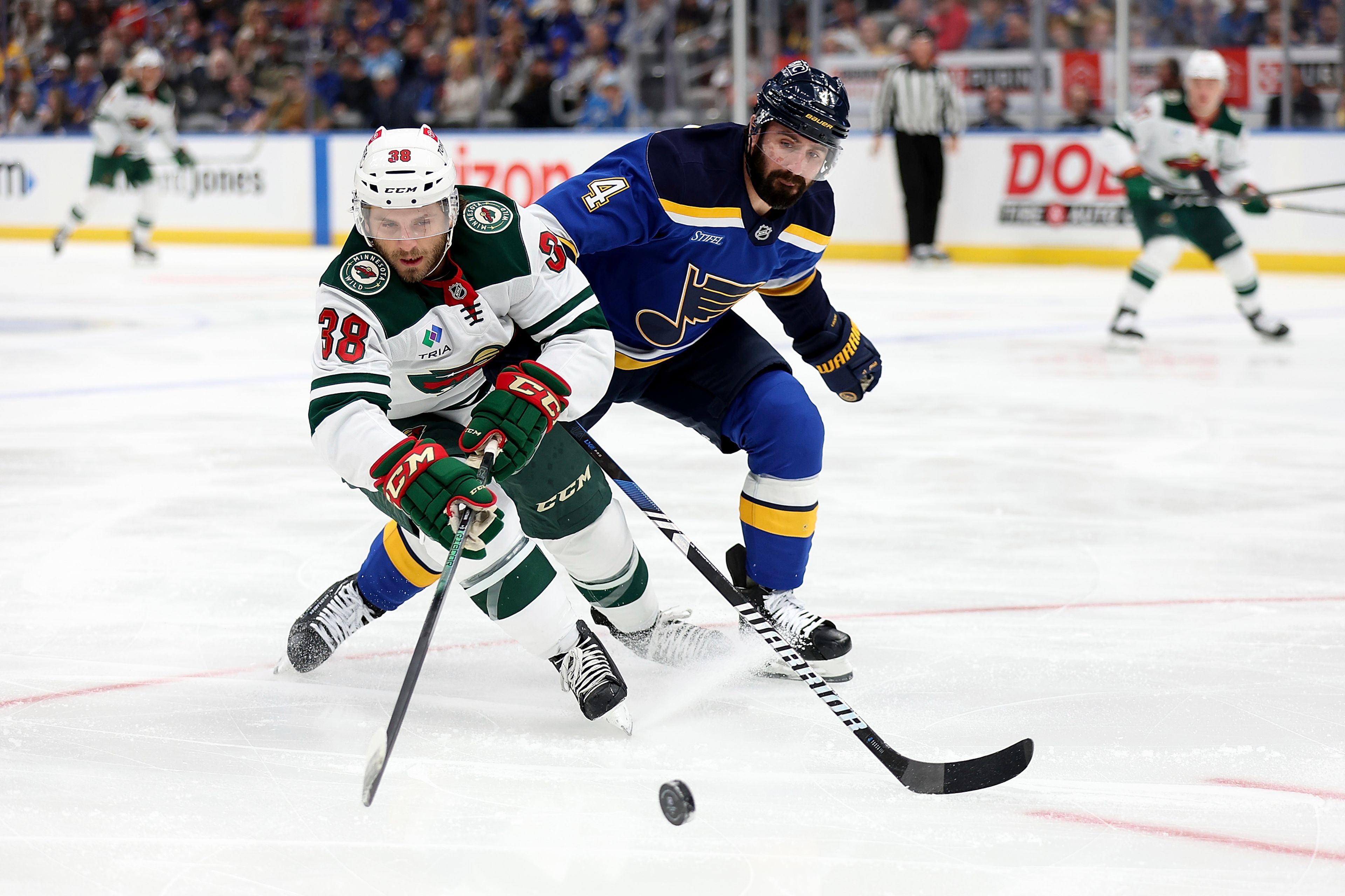 Minnesota Wild's Ryan Hartman (38) and St. Louis Blues' Nick Leddy (4) vie for control of the puck during the first period of an NHL hockey game Tuesday, Oct. 15, 2024, in St. Louis. (AP Photo/Scott Kane)