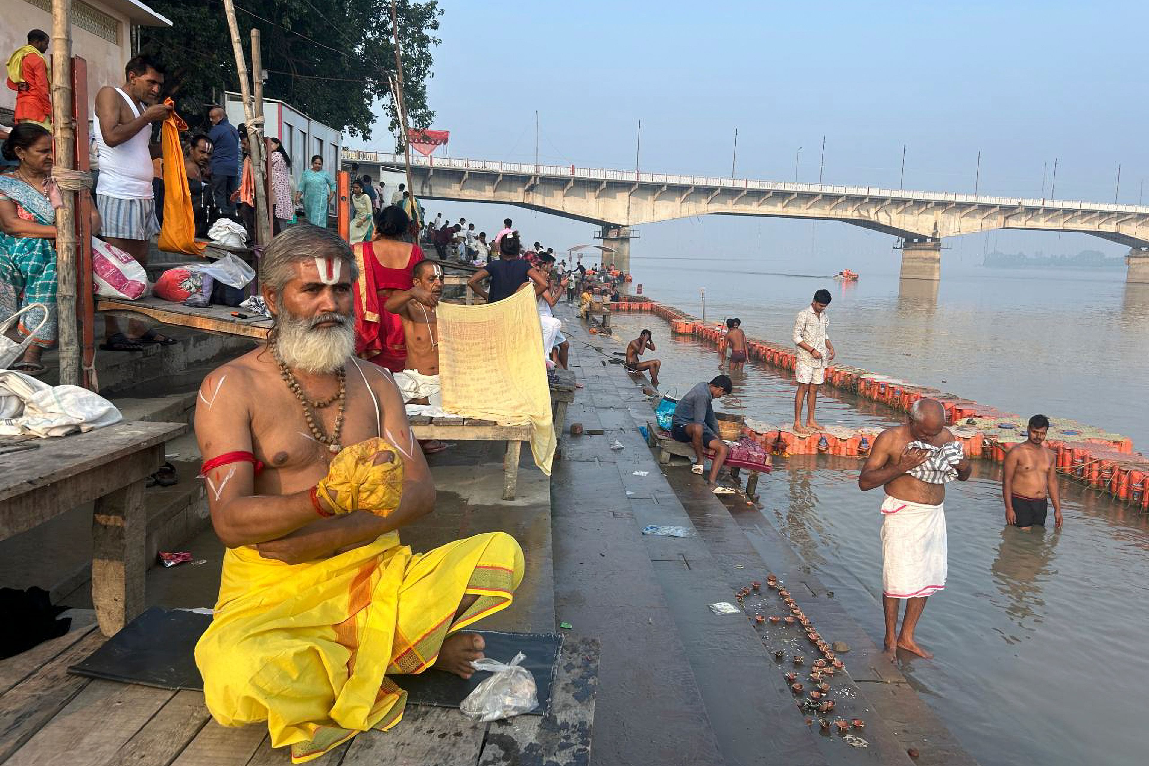 A Hindu priest prays as devotees take a holy dip in the Saryu river on the morning of Deepotsav celebrations, an event organized by the Uttar Pradesh state government on the eve of Diwali, in Ayodhya, India, Wednesday, Oct. 30, 2024. (AP Photo/Rajesh Kumar Singh)