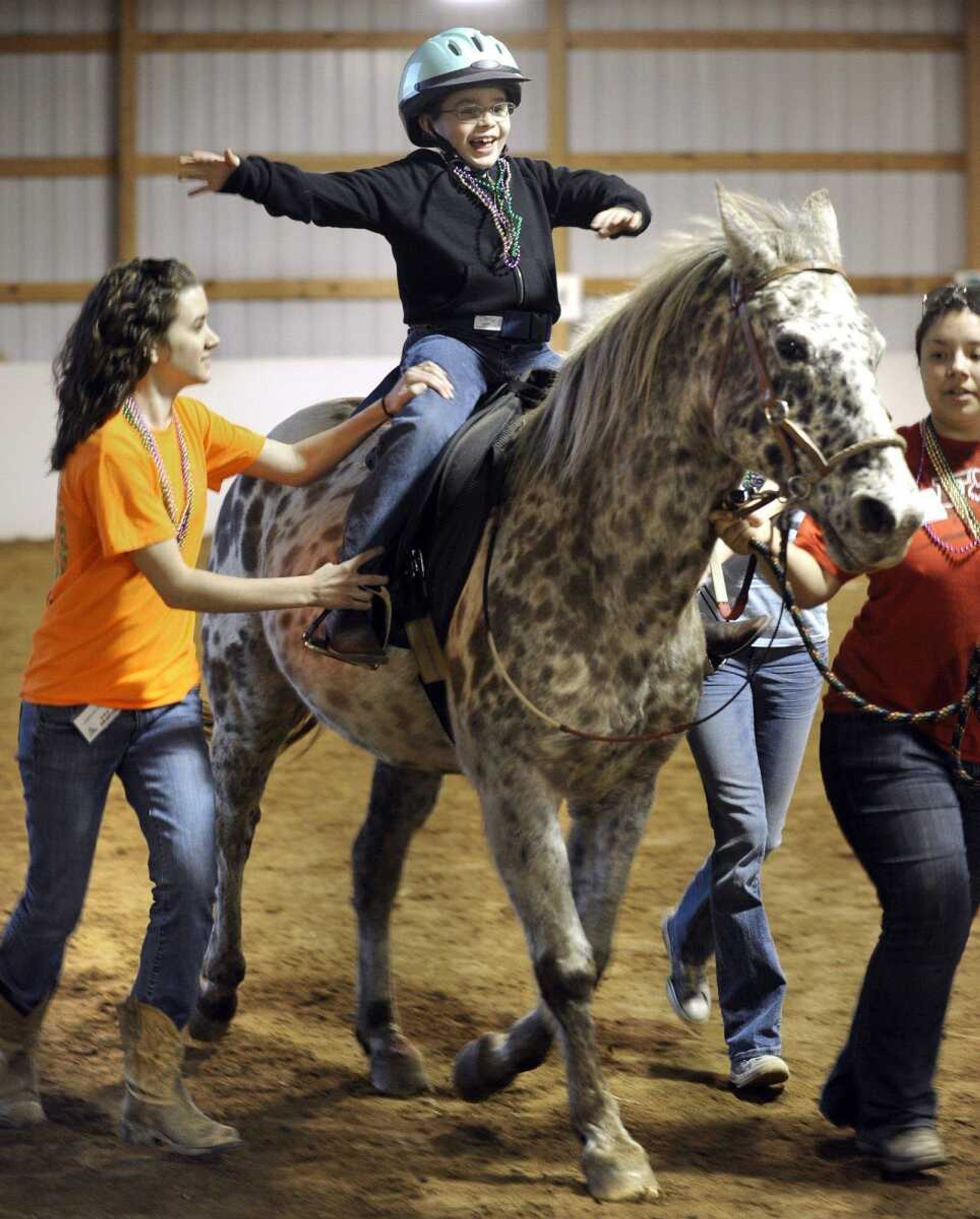 Michael Foltz rides with "airplane arms" with assistants Kristin Cook, left, and Andrea Artadi during a lesson Thursday, Feb. 23, 2012 with Mississippi Valley Therapeutic Horsemanship. (Fred Lynch)