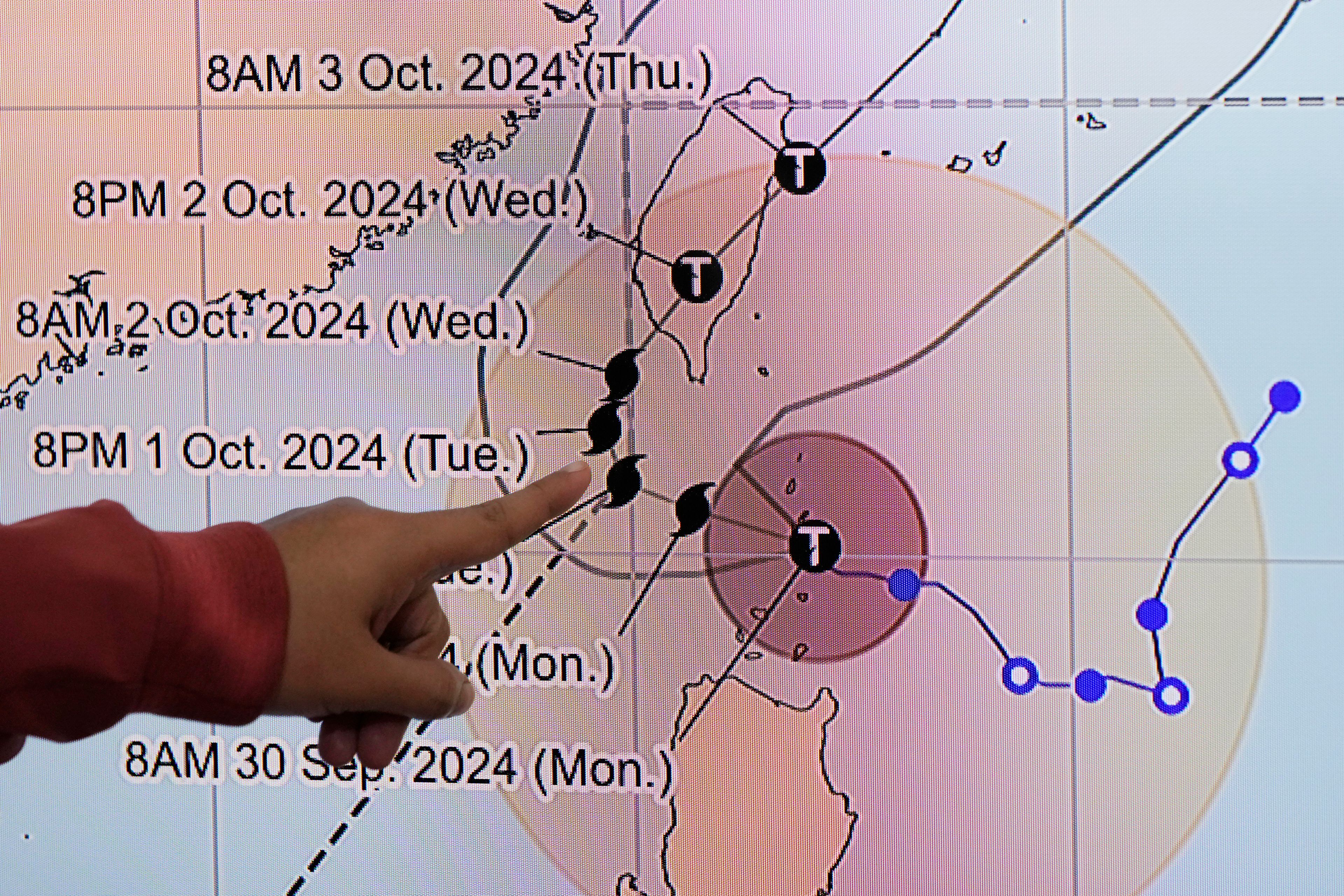 Philippine Atmospheric, Geophysical and Astronomical Services Administration weather specialist Veronica Torres points at the path of powerful Typhoon Krathon on Monday, Sept. 30, 2024, in Quezon city, Philippines as it is projected to go towards Taiwan the next day after hitting northern Philippines. (AP Photo/Aaron Favila)