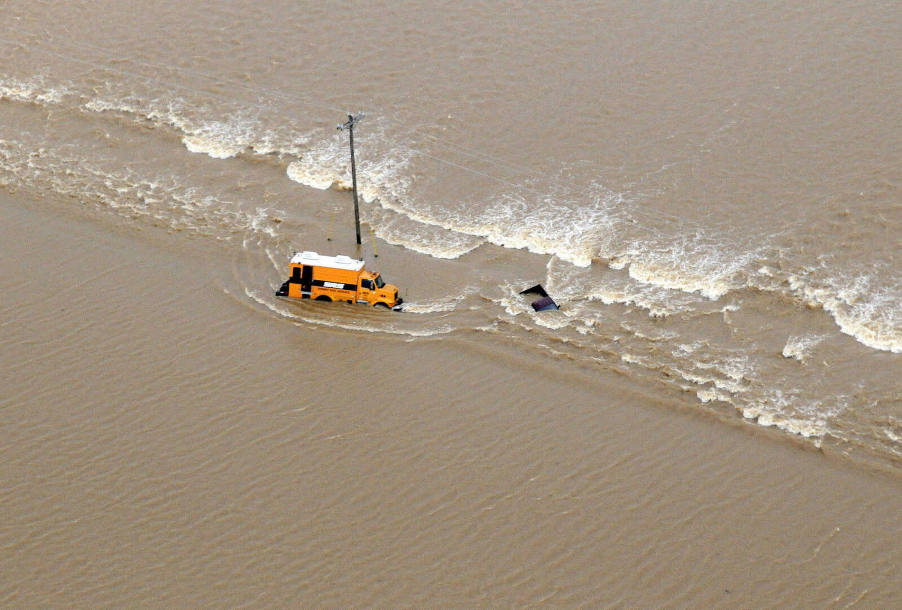 A pickup truck and armored delivery vehicle sit stranded in floodwaters from the Black River south of Poplar Bluff, Mo., Monday, April 25, 2011, along Highway 53. (AP Photo/Daily American Republic, Paul Davis)