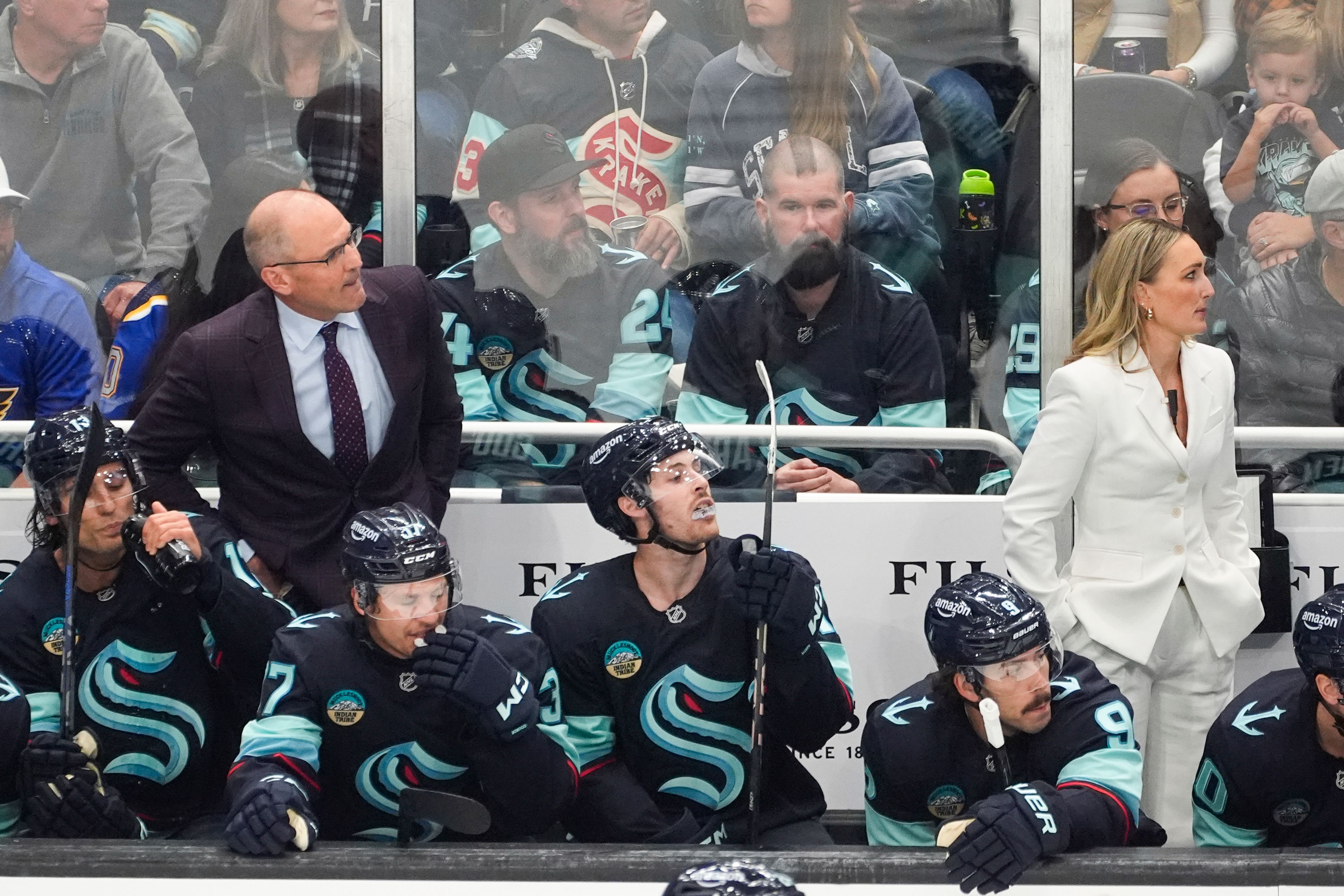 Seattle Kraken head coach Dan Bylsma, left back, and assistant coach Jessica Campbell, right back, look on during the first period of an NHL hockey game against the St. Louis Blues, Tuesday, Oct. 8, 2024, in Seattle. (AP Photo/Lindsey Wasson)