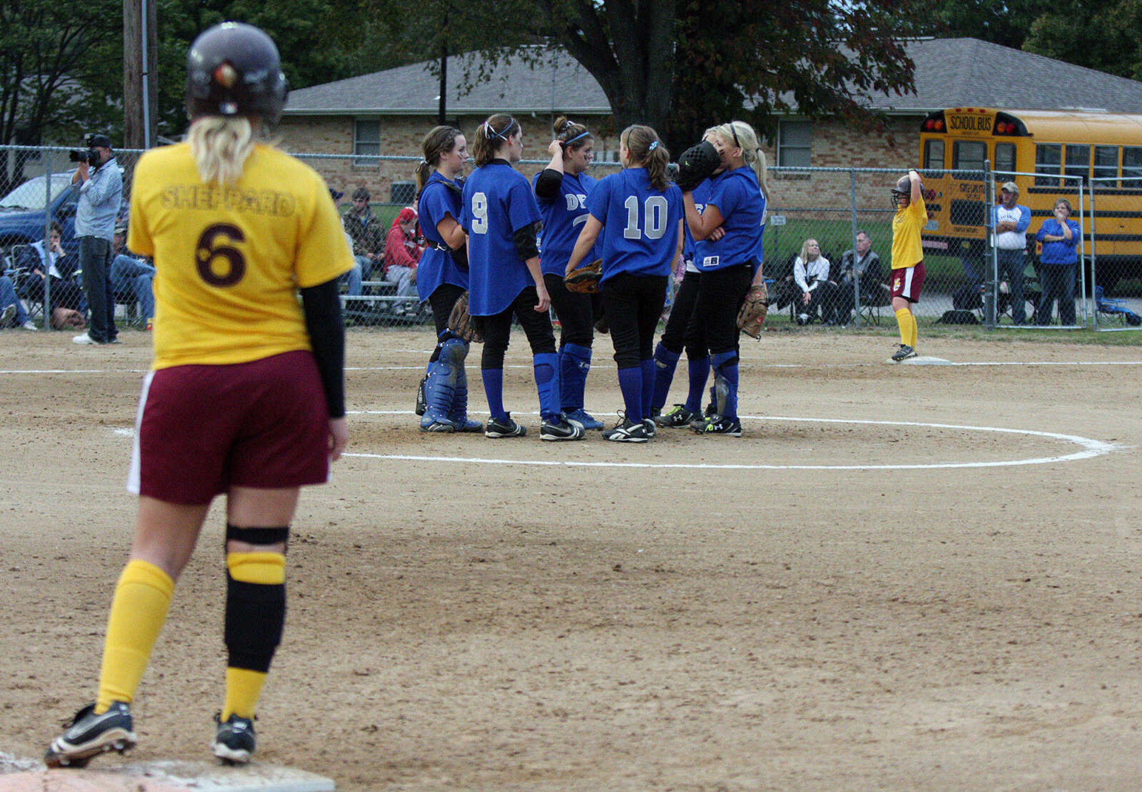 Delta Lady Bobcats huddle on the pitcher's mound while Neelyville have the bases loaded.