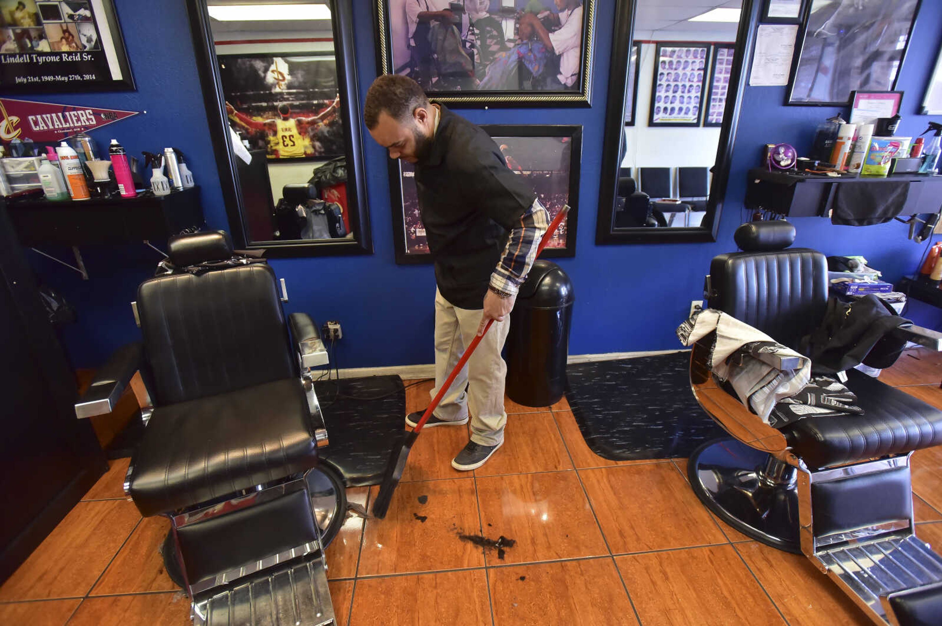 Between haircuts Chuck Reid sweeps up remains of hair at The Shop Friday, Jan. 6, 2017 at 821 Broadway in Cape Girardeau.