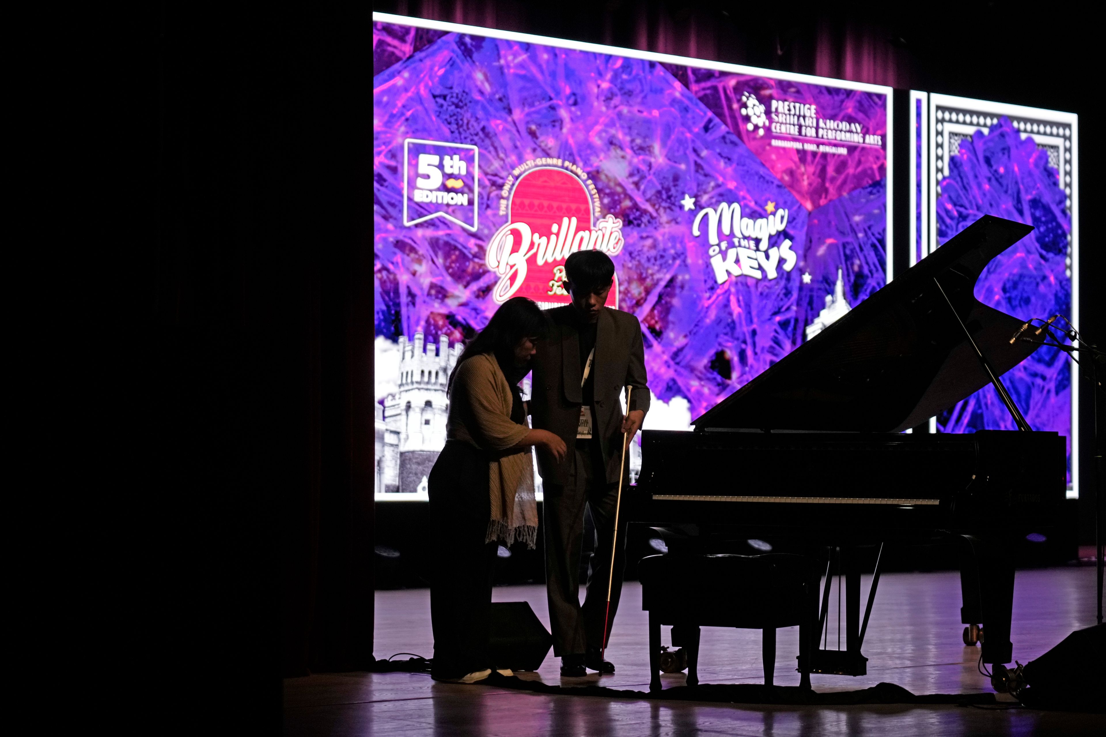 Imlibenla Jamir, 30, left, guides her brother Takosangba Jamir, 27, a blind pianist, to the stage for his performance at the two-day Brillante Piano Festival in Bengaluru, India, Sunday, Sept. 29, 2024. (AP Photo/Aijaz Rahi)