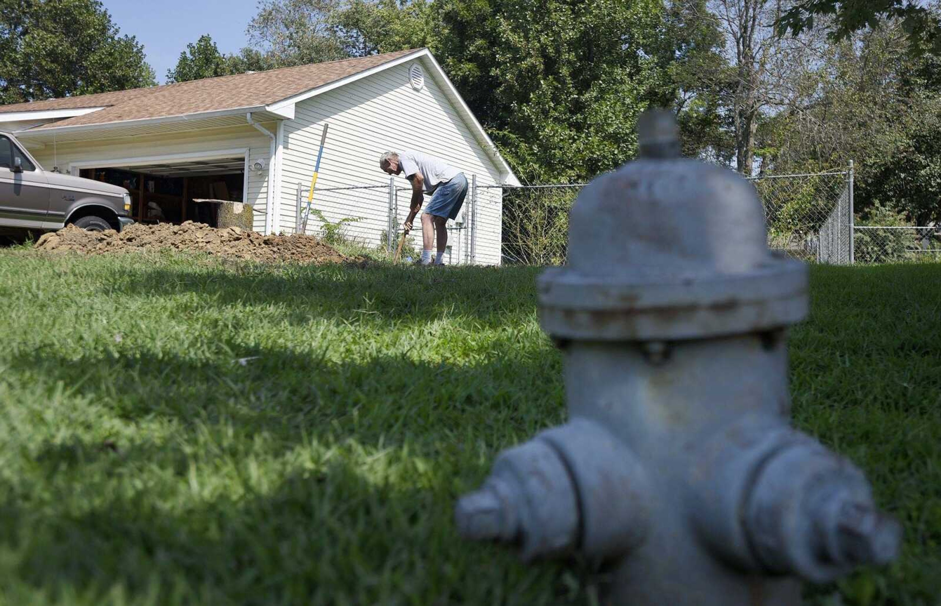 Gary Minor works to remove a tree stump and roots from his yard Wednesday in the Hillcrest Subdivision. "I would pay somebody to do this, but I can't. I have to pay my water bill," Minor said.