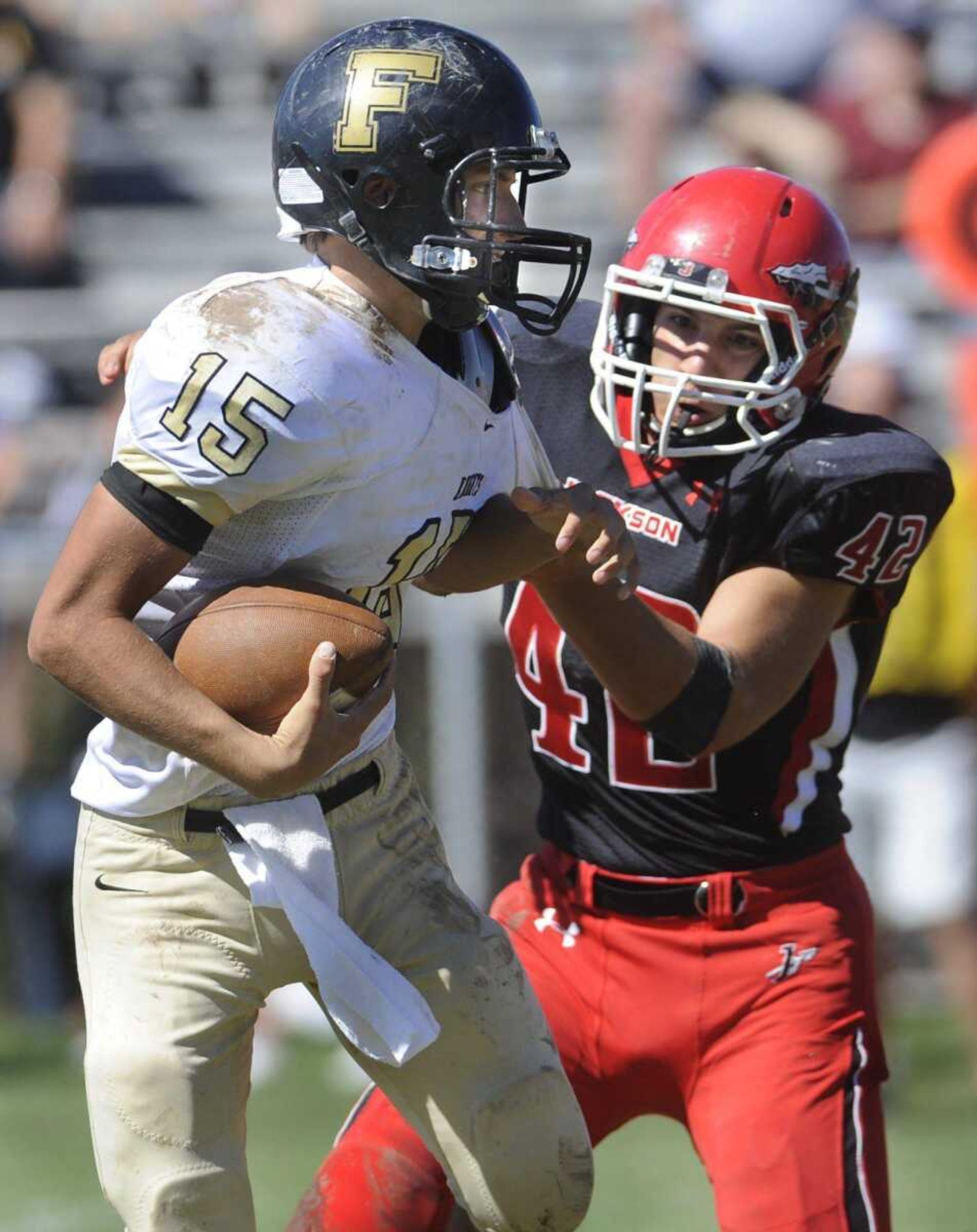 Farmington quarterback Justin Boehm tries to escape a tackle by Jackson&#8217;s Ken Maudie during the second quarter Saturday at Jackson High School. (Fred Lynch)