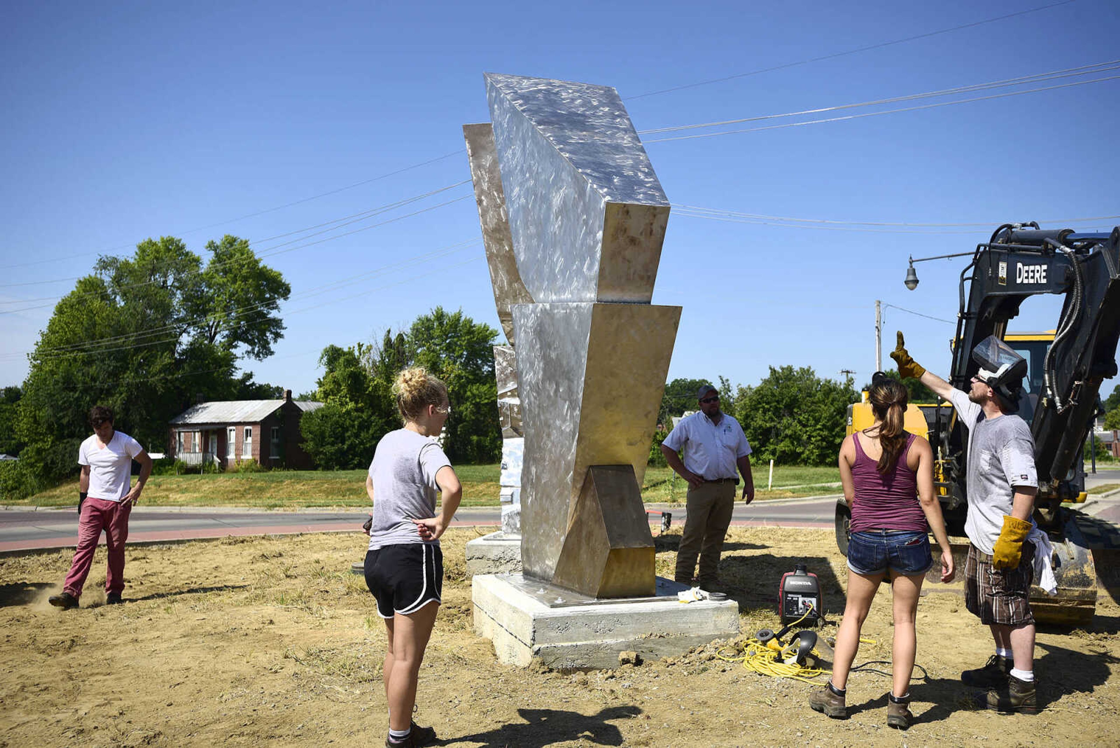 Chris Wubbena and his current and former students, Terry Davis, Vatchae Sams, Jessica Lambert, Brigit Ciskowski and Deanna Hoffman put the finishing touches together after the installation of Wubbena's 14-foot sculpture, "Commence", in the Fountain Street roundabout on Monday, July 24, 2017, near the River Campus. The students helped build the sculpture.