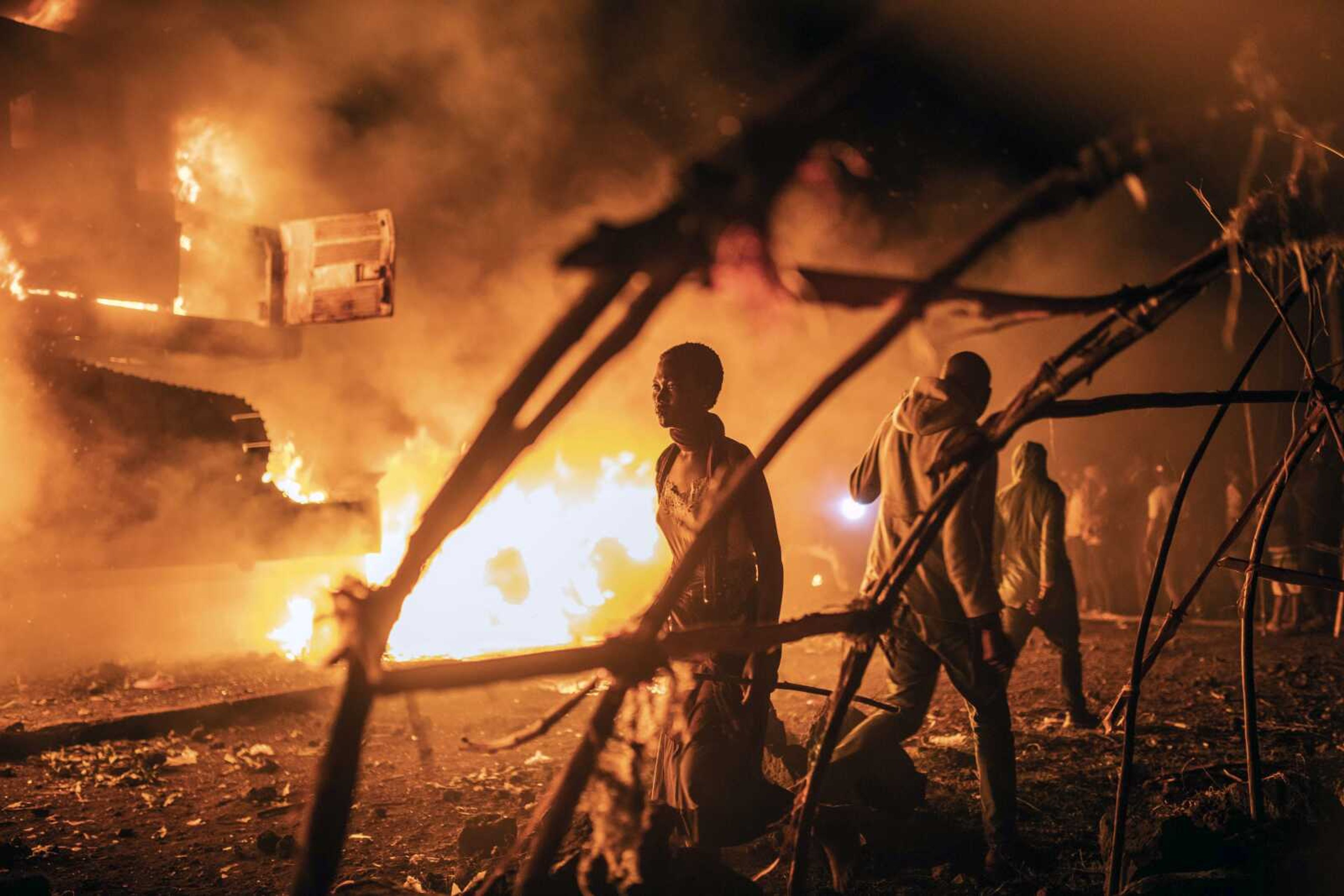 People walk by U.N. vehicles that were set on fire in Goma, Democratic Republic of Congo, on Nov. 1. Angry crowds in eastern Congo have set fire to U.N. vehicles as frustrations mount over the advance of M23 rebels.