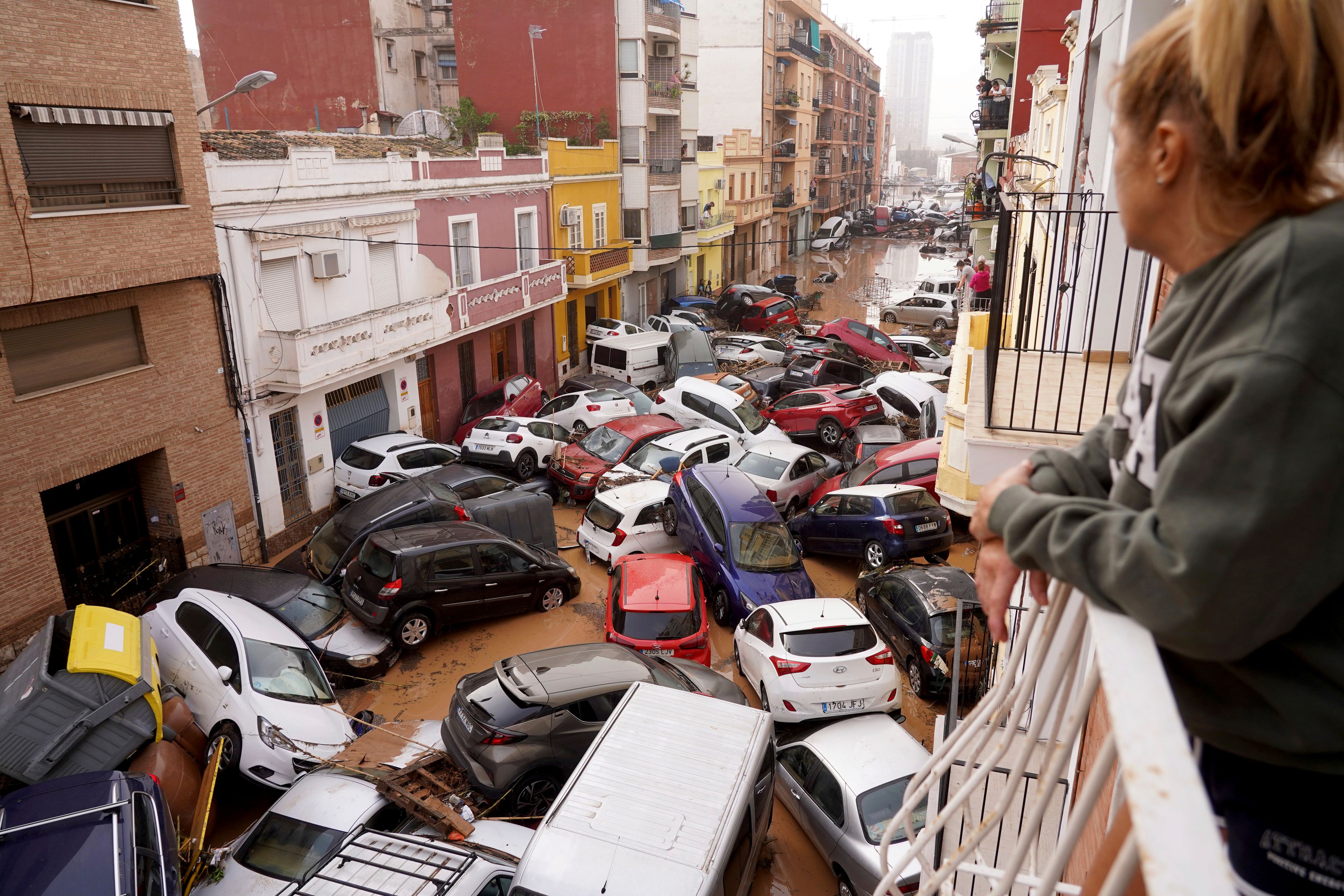 A woman looks out from her balcony as vehicles are trapped in the street during flooding in Valencia, Wednesday, Oct. 30, 2024. (AP Photo/Alberto Saiz)