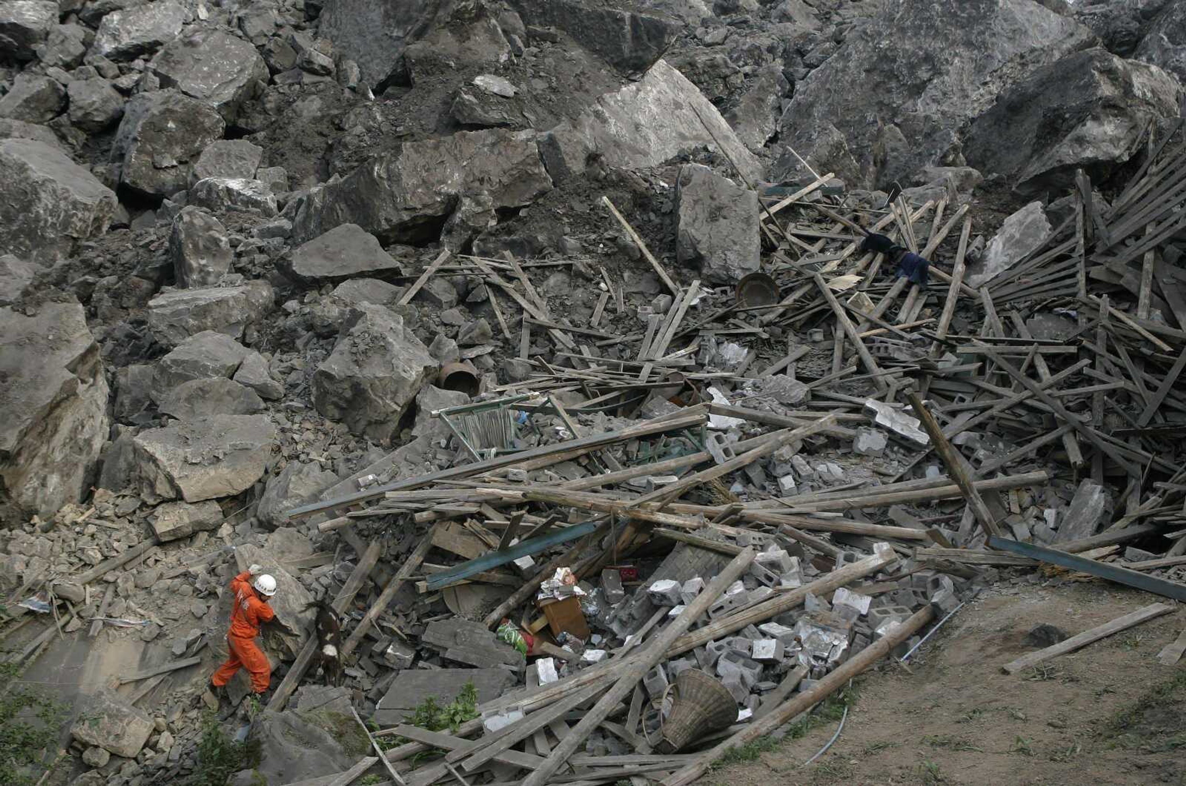 A rescuer search for survivors at the site where a landslide occurred Friday in Wulong county in southwest China's Chongqing Municipality, Saturday June 6, 2009. A landslide buried an iron ore plant and several homes, killing at least 26 people and leaving dozens missing in a valley in southwestern China, state television said Saturday. (AP Photo) ** CHINA OUT **