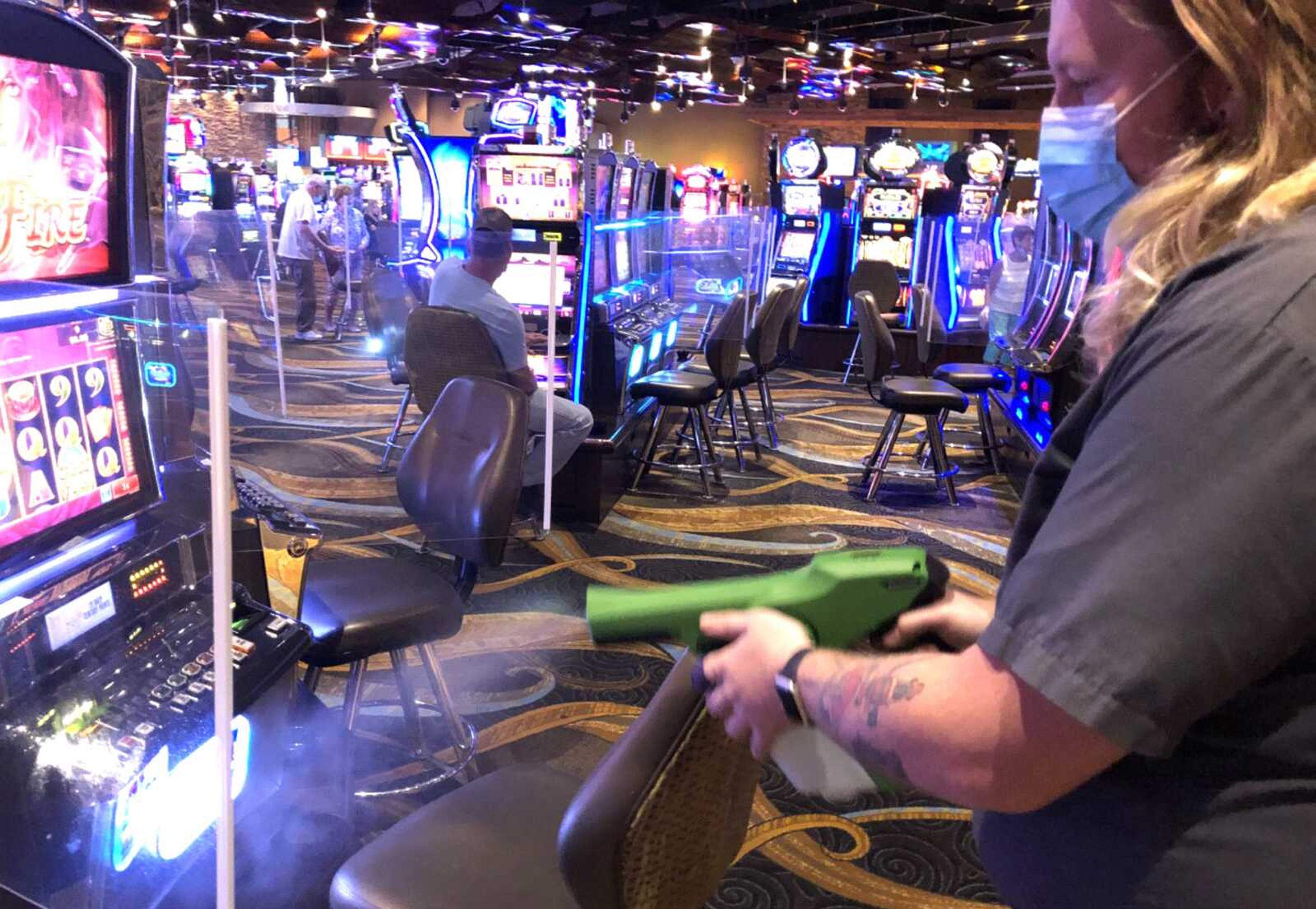 Century Casino Cape Girardeau employee Curtis Chiles uses a fogger to sanitize slot machines on the casino's gaming floor.