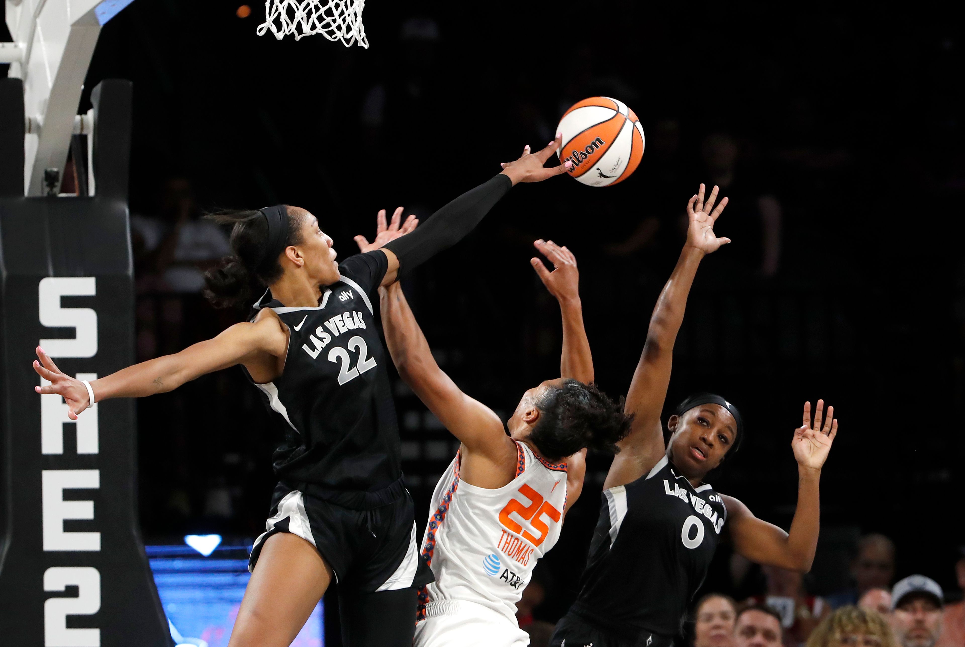 Connecticut Sun forward Alyssa Thomas (25) is fouled as she tries to shoot between Las Vegas Aces center A'ja Wilson (22) and guard Jackie Young (0) during the first half of a WNBA basketball game Sunday, Sept. 15, 2024, in Las Vegas. (Steve Marcus/Las Vegas Sun via AP)