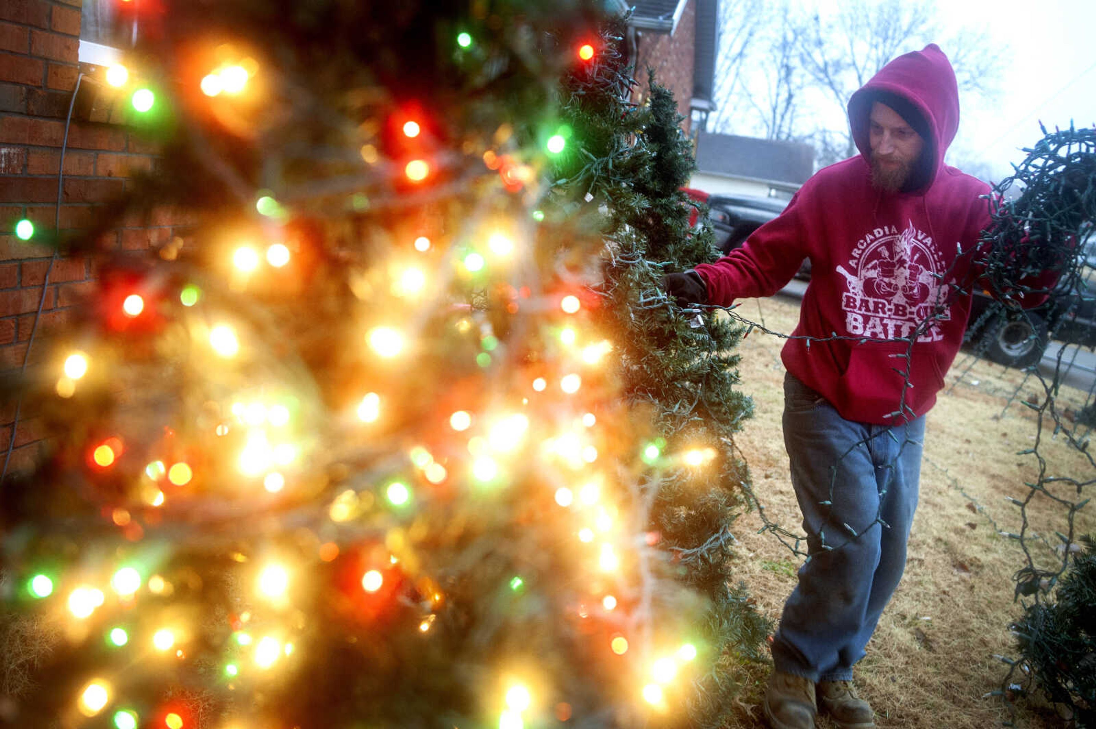 Adam Rister wraps a tree in Christmas lights outside his home Thursday, Nov. 21, 2019, in Chaffee, Missouri. Rister began assembling Christmas light displays when he was about 8; now roughly two-and-a-half decades later, it's a passion. "It's growing every year. Little by little," he said. "I have a passion for doing it." Rister said when he was a kid, his grandparents, Mary and Gail Rister, were older and didn't want to mess with Christmas displays as much. So his grandpa gave him a box of lights and told him he could decorate. As a little kid, he said it was something he always wanted to do.