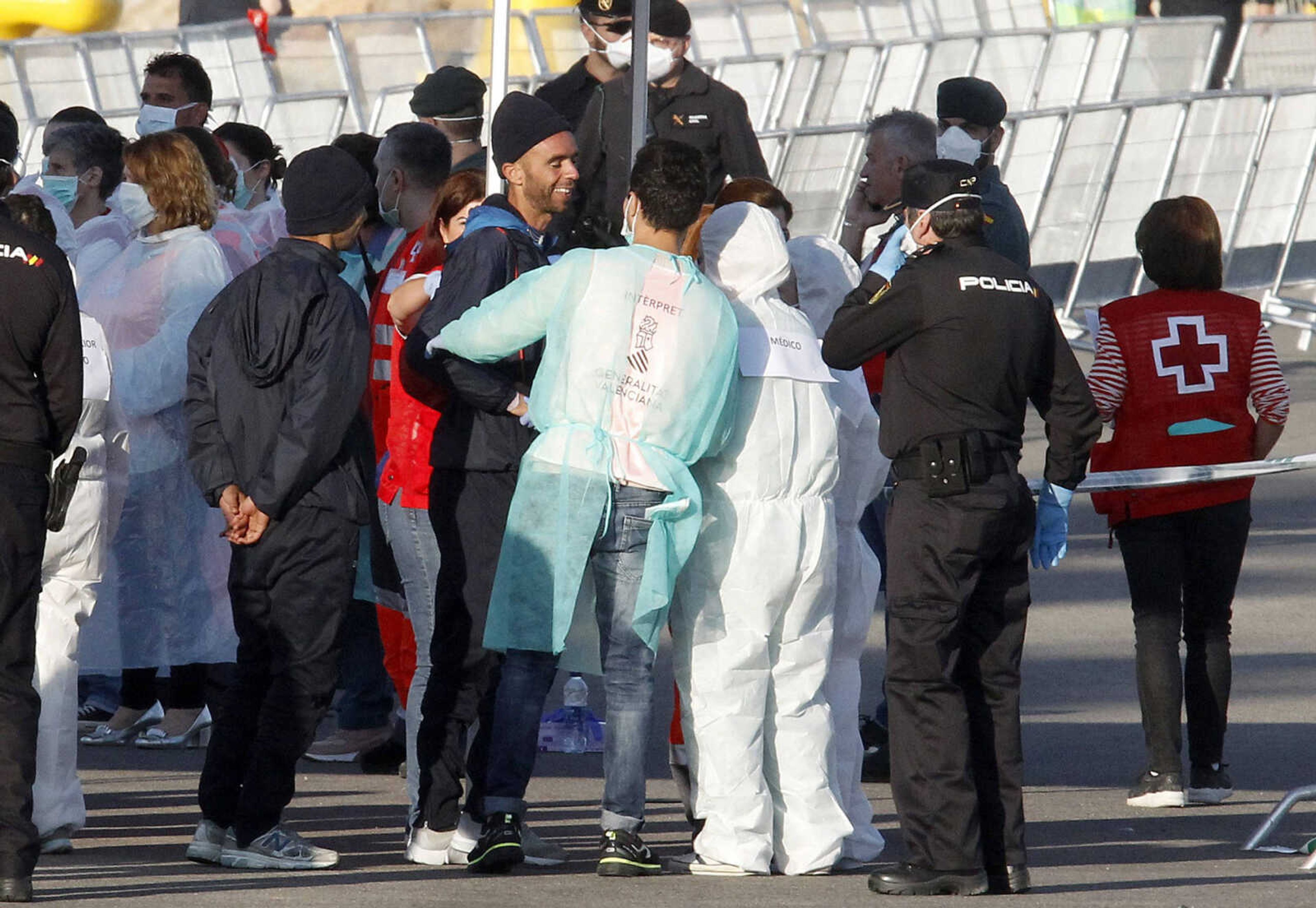 Migrants are met by emergency workers after descending the Italian coast guard vessel Dattilo on Sunday upon arrival at the eastern port of Valencia, Spain,.