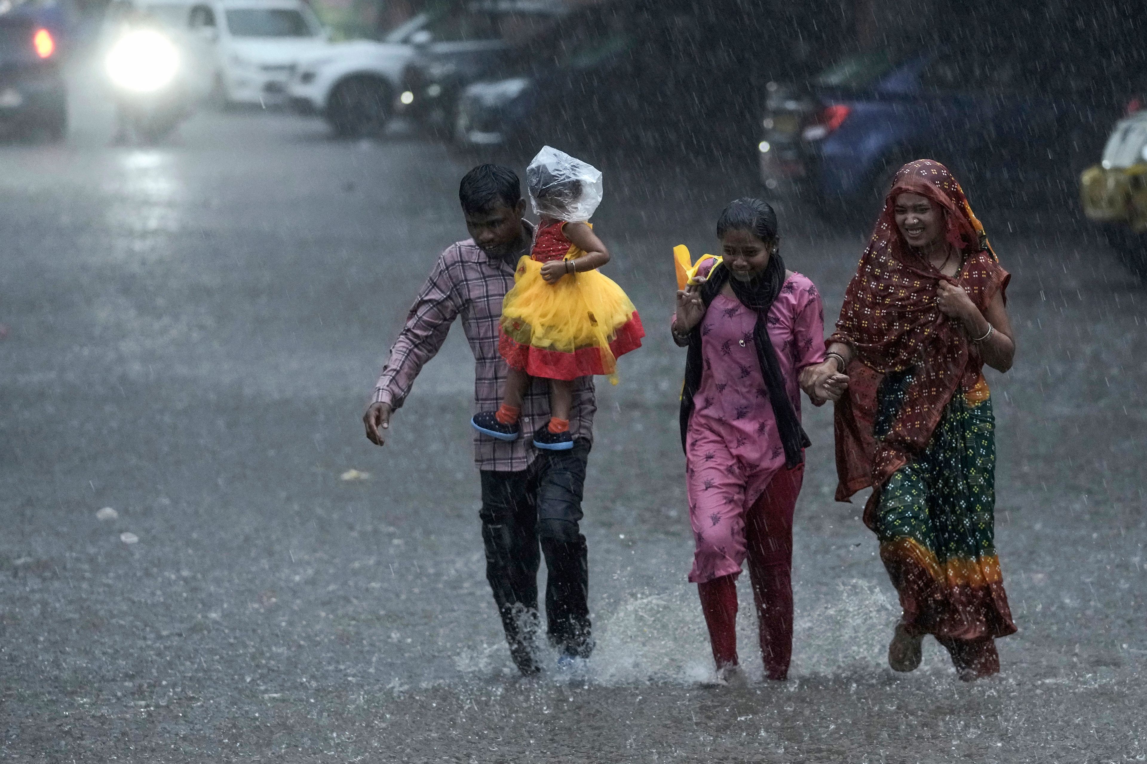 A family run as they cross a street during heavy rain in Hyderabad, India, Friday, Sept. 6, 2024. (AP Photo/Mahesh Kumar A.)