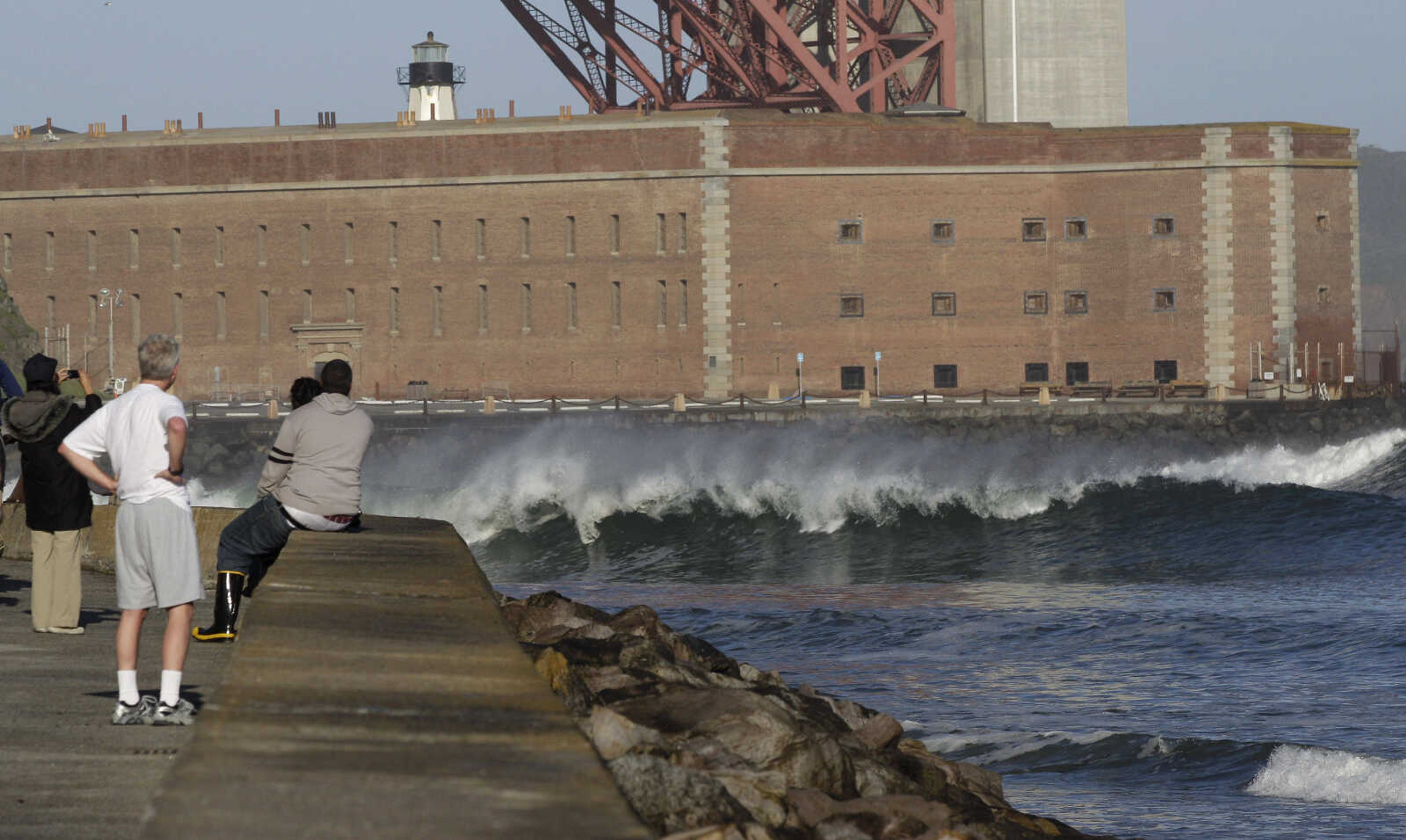 With a tsunami warning in effect for Northern California, a group of people watch as a wave hits near Fort Point under the Golden Gate Bridge in San Francisco on Friday, March 11, 2011. The warnings came after a 8.9-magnitude earthquake and tsunami struck Japan. (AP Photo/Jeff Chiu)