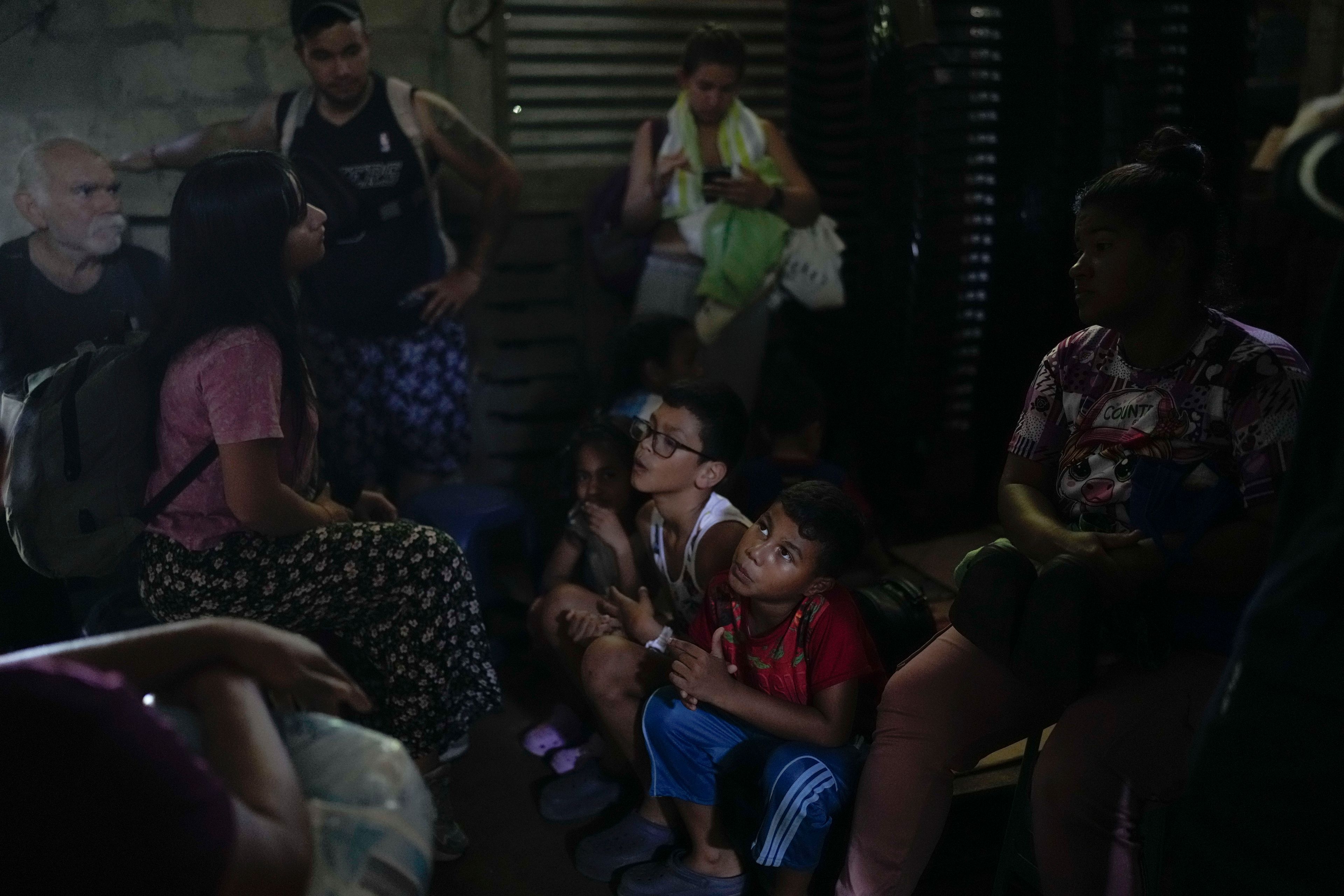 Venezuelan migrant Daniel Dura, second from right, waits next to his mother Rannely Duran inside a house before crossing the Suchiate River, which marks the border between Guatemala and Mexico, from Tecun Uman, Guatemala, Sunday, Oct. 27, 2024. (AP Photo/Matias Delacroix)