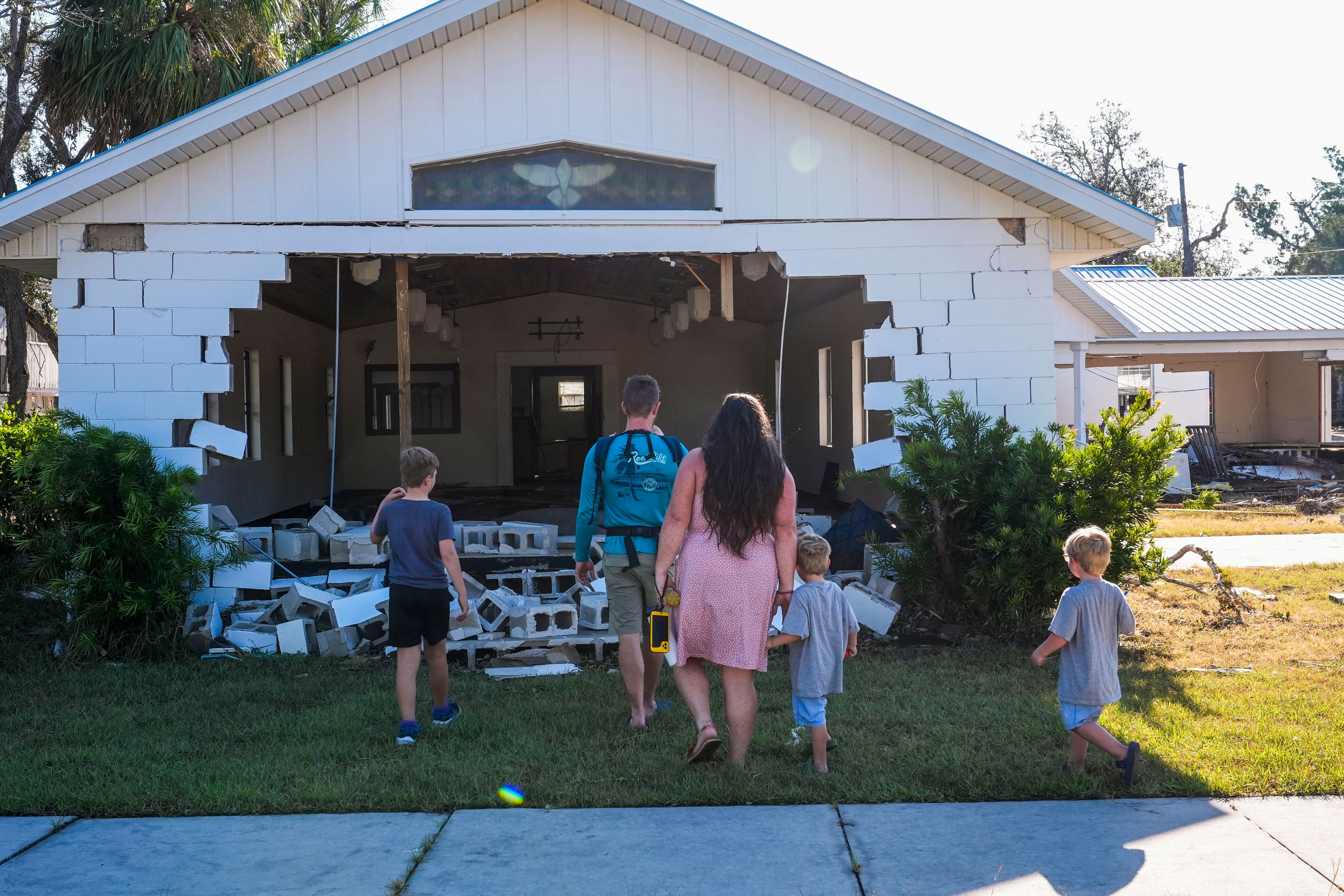 A group from St. Augustine, Fla. that arrived to help storm victims, who did not want to give their names, pray outside the damaged First Baptist Church in the aftermath of Hurricane Helene, in Horseshoe Beach, Fla., Sunday, Sept. 29, 2024. (AP Photo/Gerald Herbert)