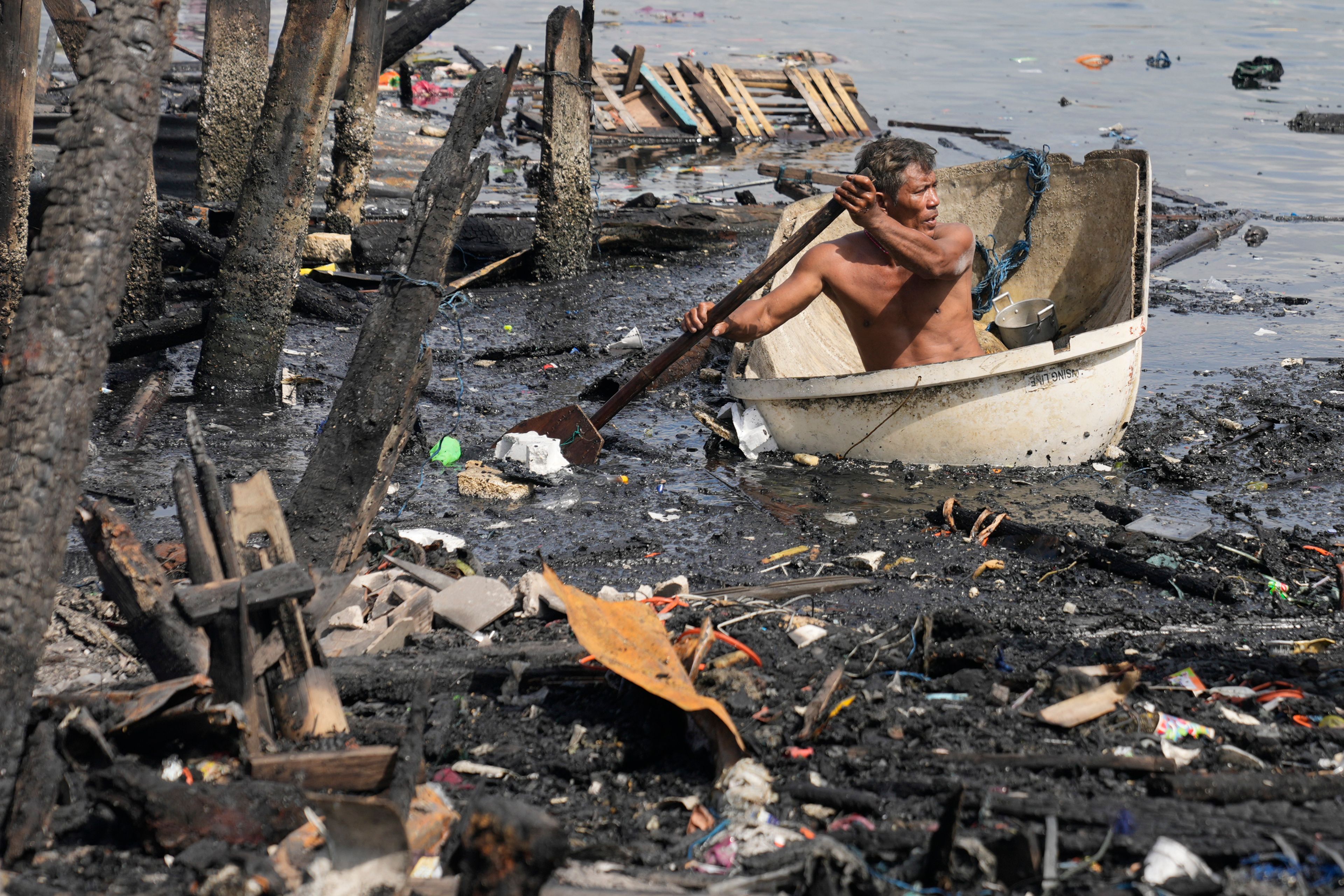 A resident returns to his burned village, Monday Nov. 25, 2024, one day after a fire broke out leaving about 2,000 families homeless at a slum area in Manila, Philippines. (AP Photo/Aaron Favila)