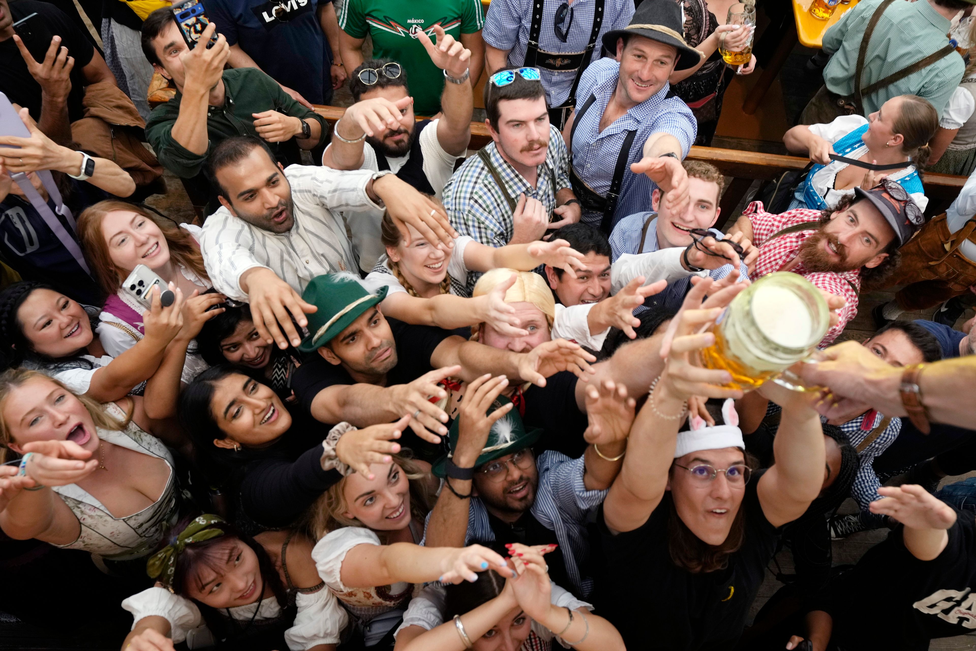 Festival goer reach out for the first glasses of beer at the Hofbraehaus beer tent, on day one of the 189th 'Oktoberfest' beer festival in Munich, Germany, Saturday, Sept. 21, 2024. (AP Photo/Matthias Schrader)