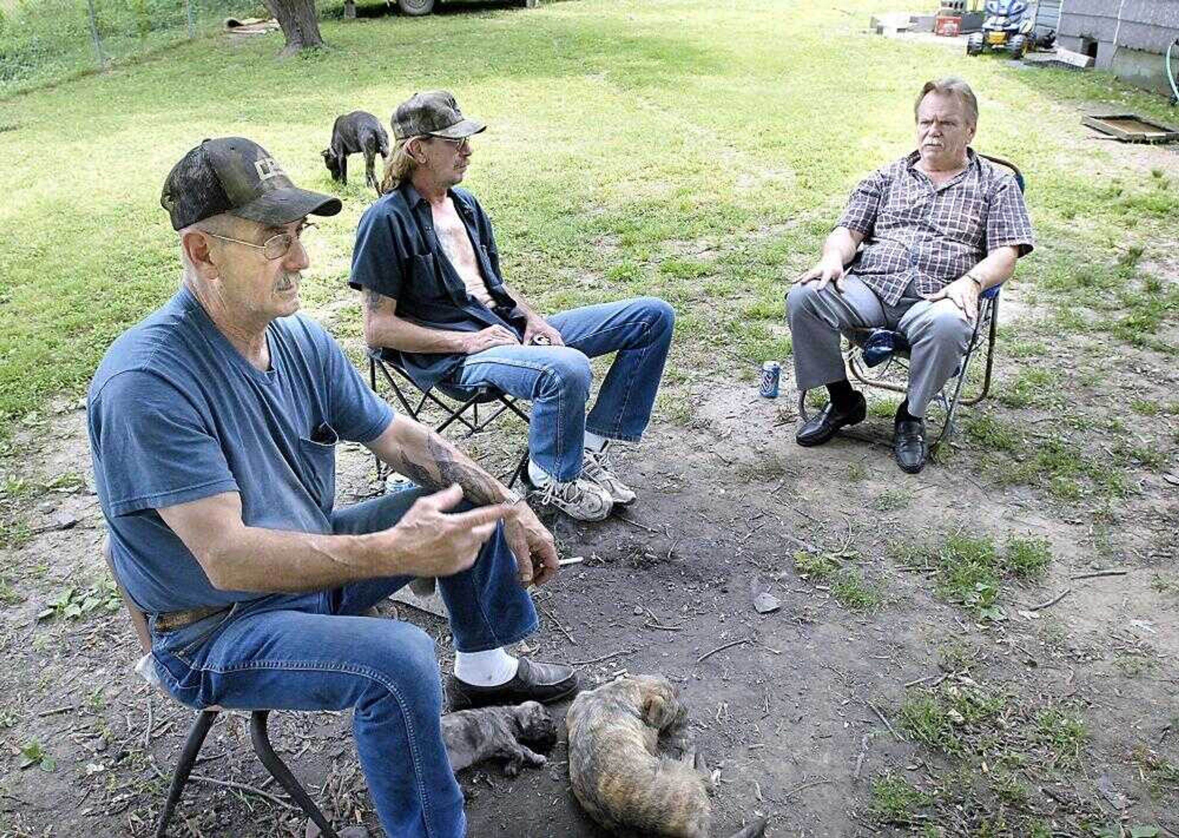 Van Brooks, left, of Thebes, Ill., talked about the problem of dogs being dumped in the Illinois town with his nephew, Terry Biller, center, and his brother, Jack Brooks. Van Brooks, who has several dogs, said roaming dogs are a problem because many people do not keep their dogs chained or fenced like he does. (Kit Doyle)