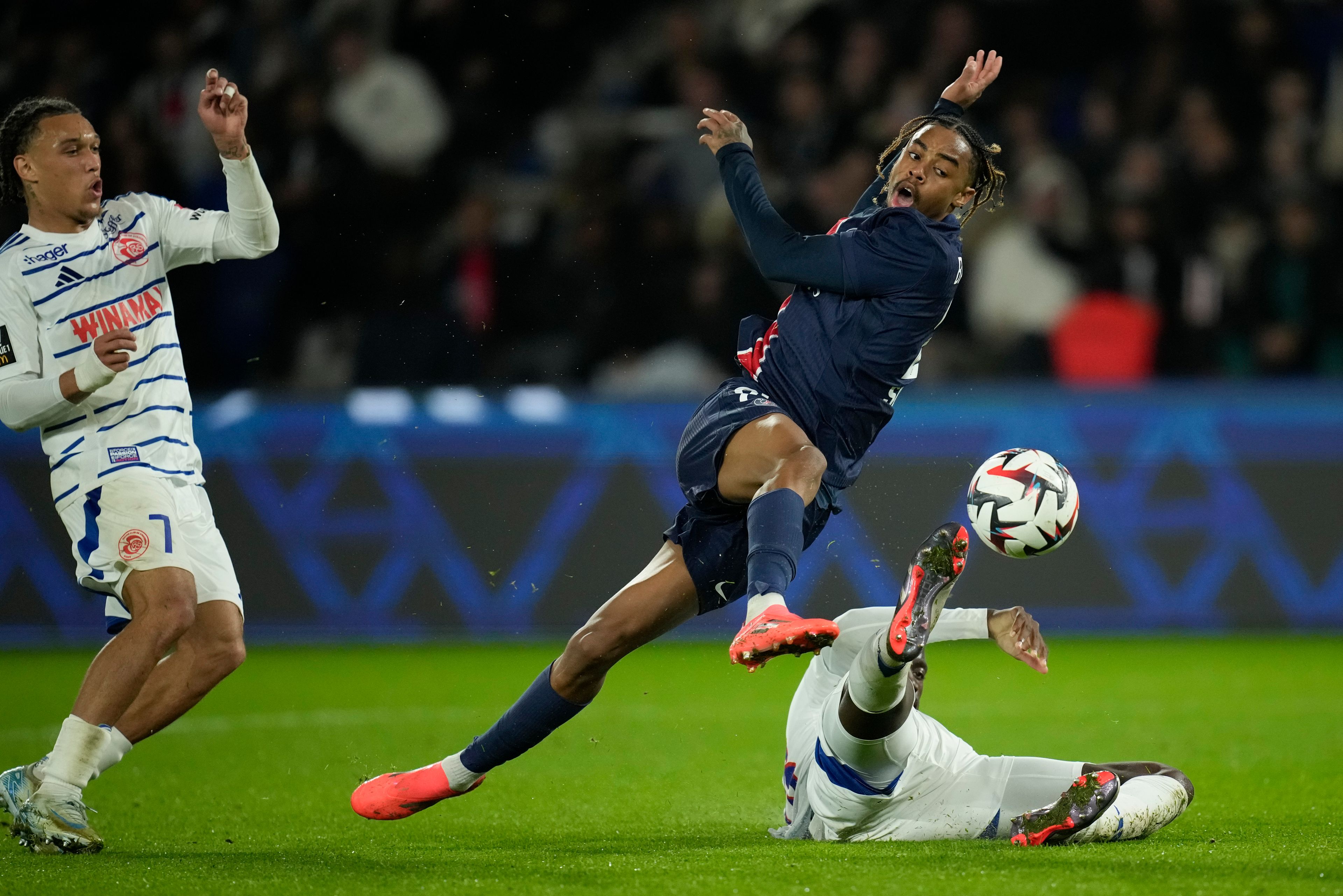 PSG's Bradley Barcola, center, gets in a shot during the French League One soccer match between Paris Saint-Germain and Strasbourg at the Parc des Princes in Paris, Saturday, Oct. 19, 2024. (AP Photo/Christophe Ena)