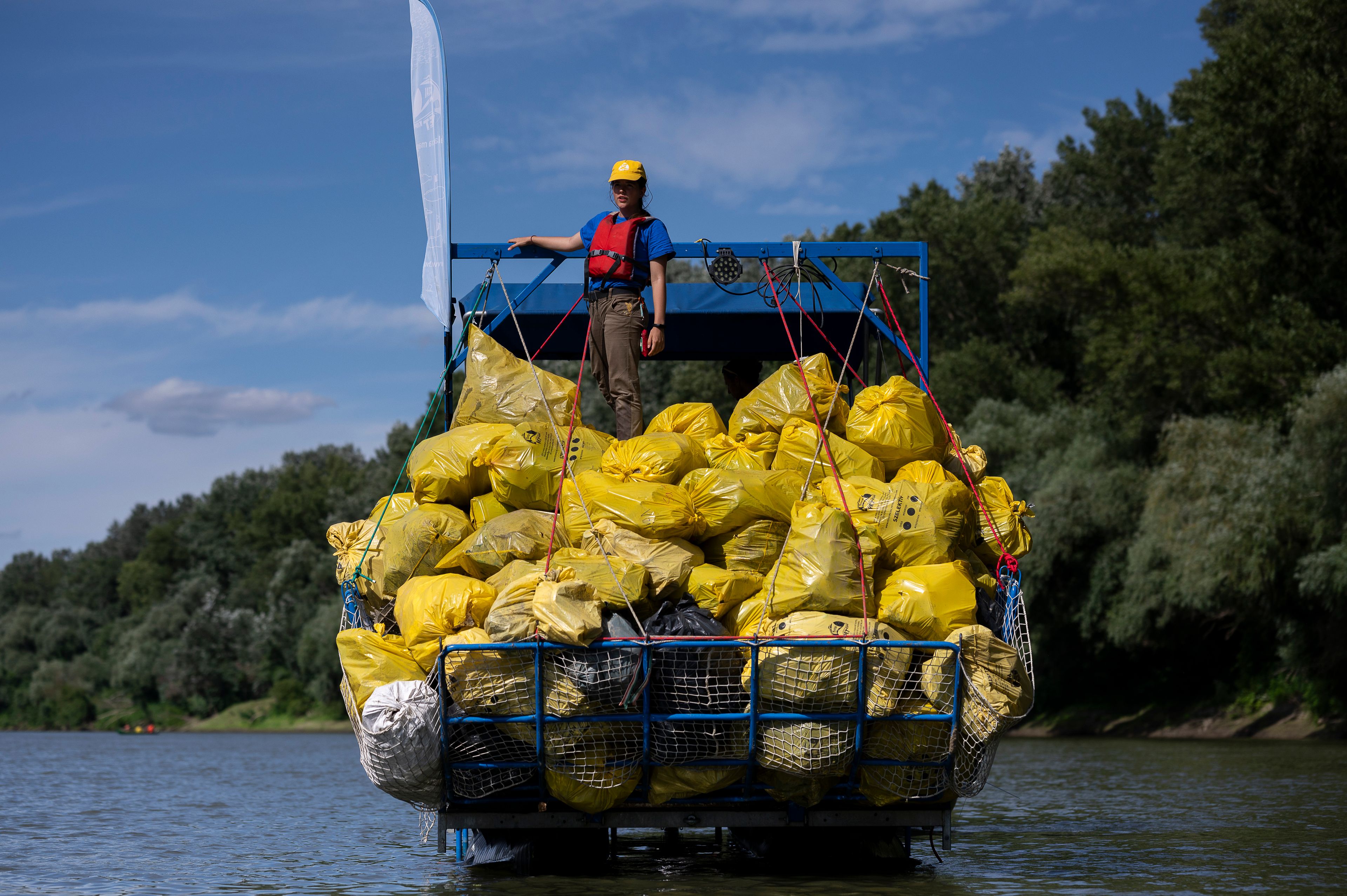 FILE - A volunteer stands on top of a pile of rubbish collected that day while participating in the Plastic Cup event near Tiszaroff, Hungary, Aug. 2, 2023. (AP Photo/Denes Erdos, File)