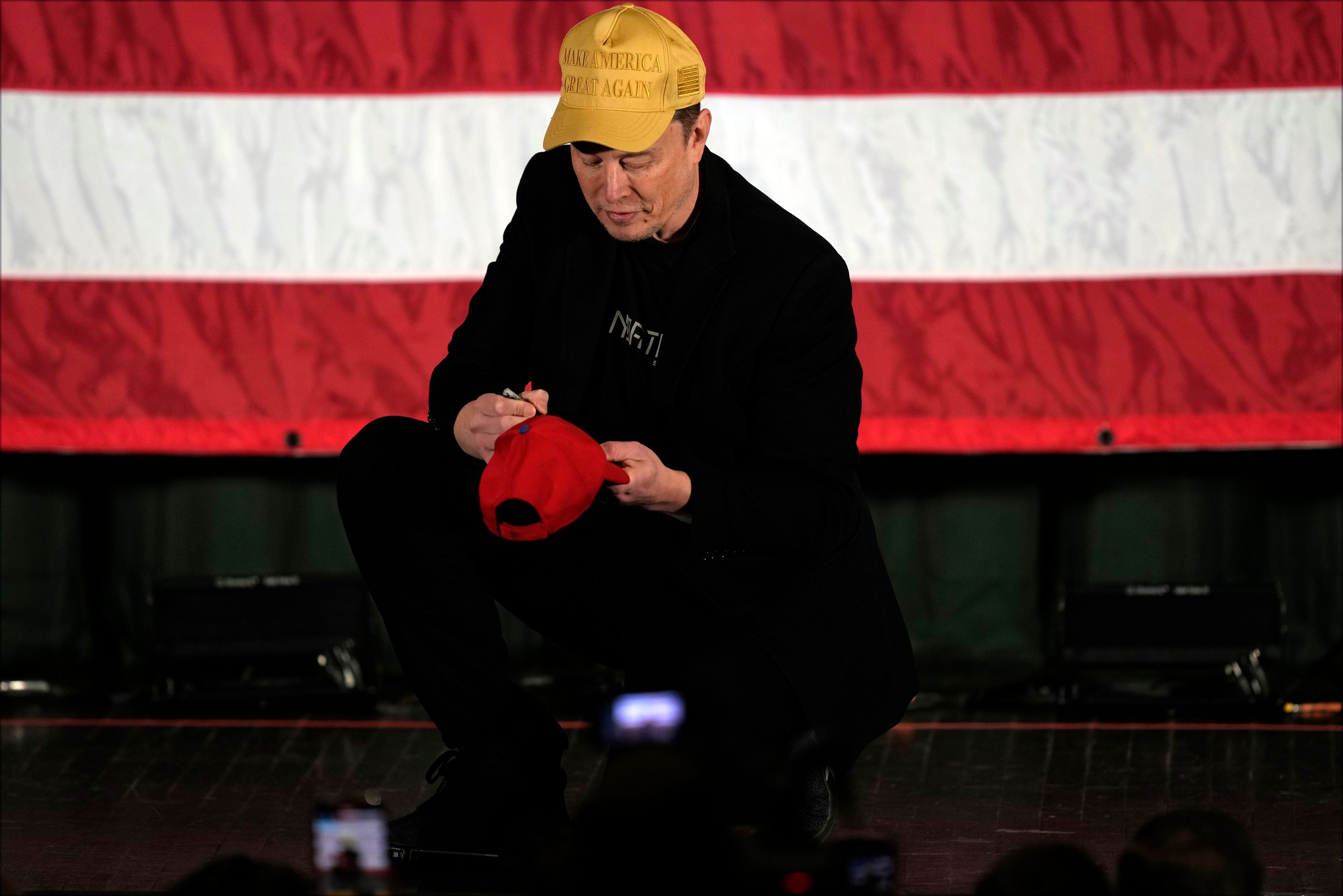 Elon Musk signs as Philadelphia Phillies hat as he speaks as part of a campaign town hall in support of Republican presidential nominee former President Donald Trump in Folsom, Pa., Thursday, Oct. 17, 2024. (AP Photo/Matt Rourke)