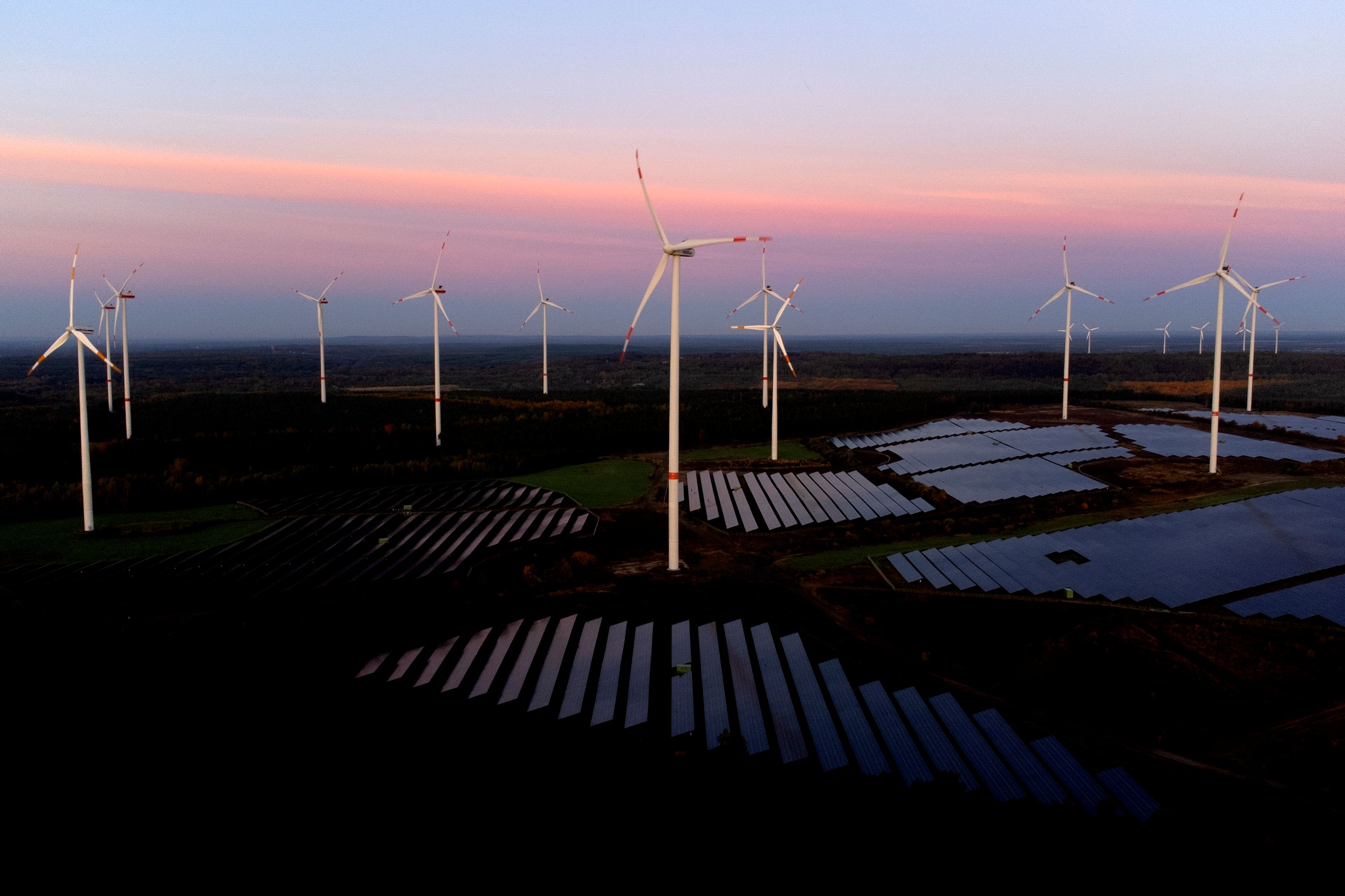 Wind turbines operate as the sun rises at the Klettwitz Nord solar energy park near Klettwitz, Germany, Wednesday, Oct. 16, 2024. (AP Photo/Matthias Schrader)