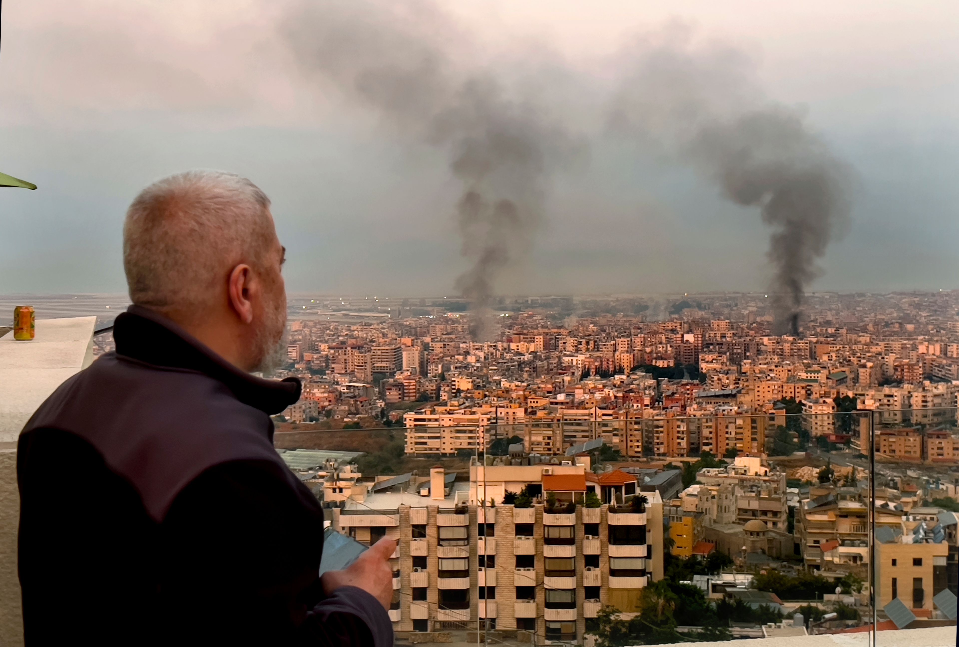 A man looks as smoke rise from Israeli airstrikes in Dahiyeh, Beirut, Lebanon, early Sunday, Oct. 6, 2024. (AP Photo/Hussein Malla)